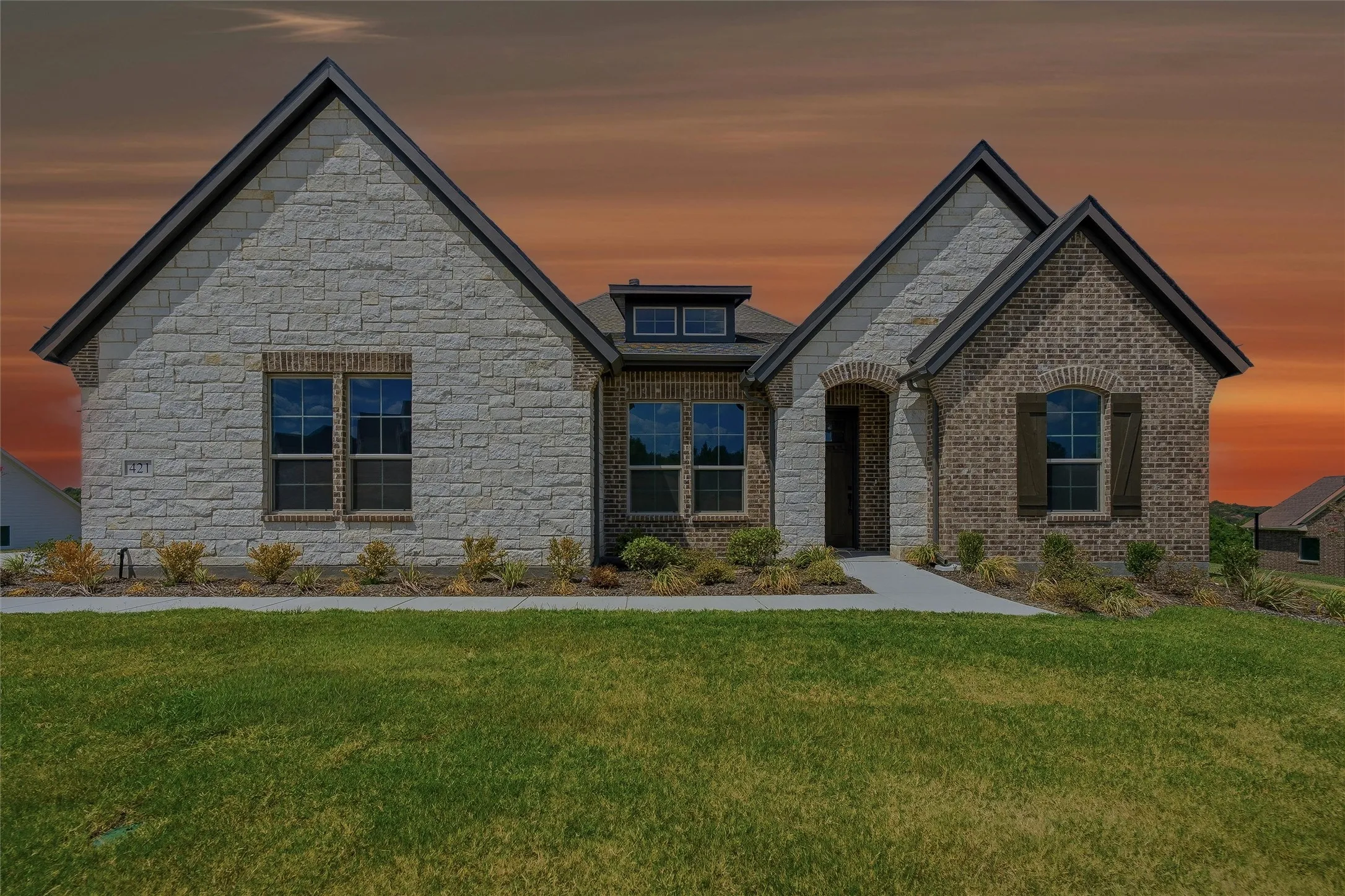 Stone and brick facade with dark trim, featuring a gabled roofline and arched entry
