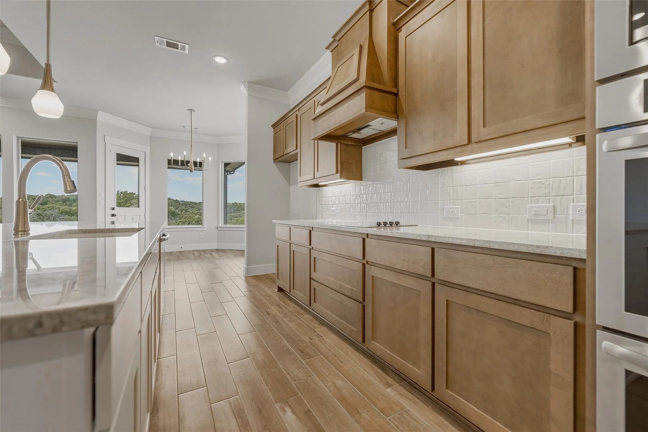Kitchen with light wood cabinetry, white subway tile backsplash, and light-toned countertops