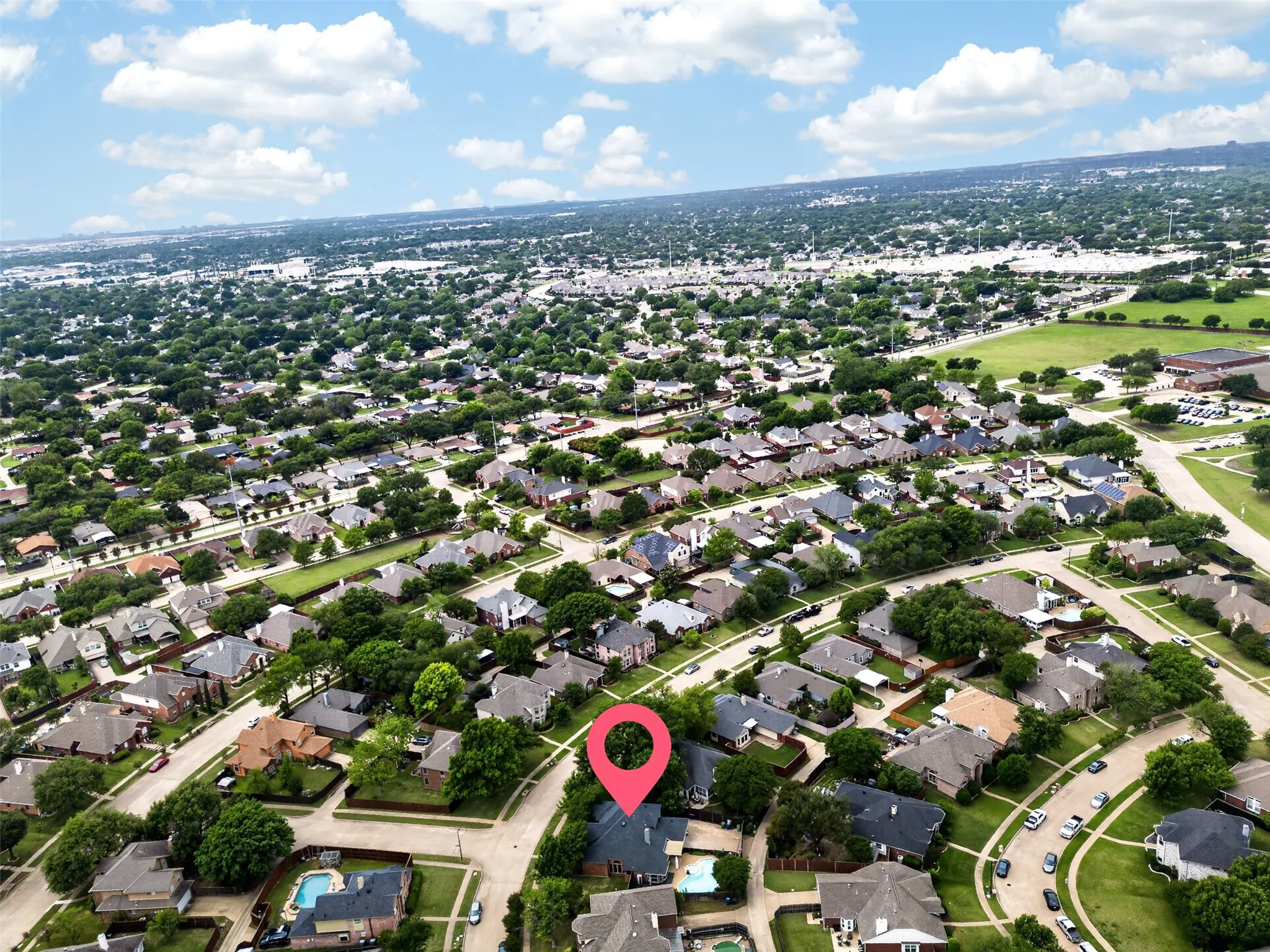 Aerial view of the property and its surrounding neighborhood, featuring numerous residential homes, streets, and abundant mature trees
