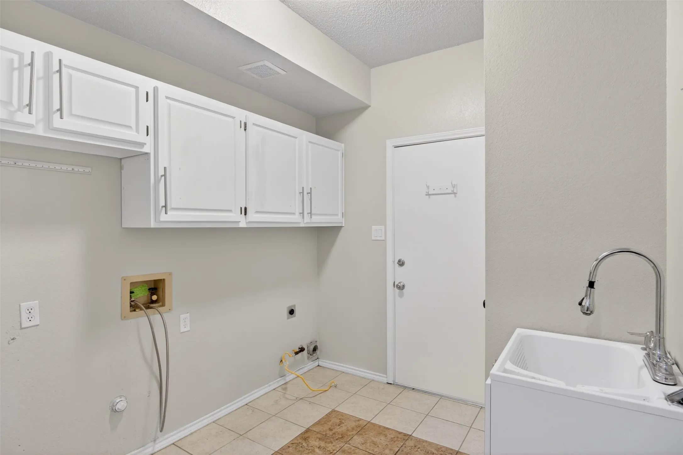 Utility room featuring white cabinetry, a utility sink with a high-arc faucet, and tiled flooring