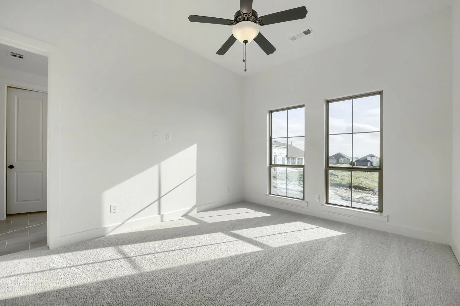 Spacious room featuring light gray carpet flooring and bright white walls