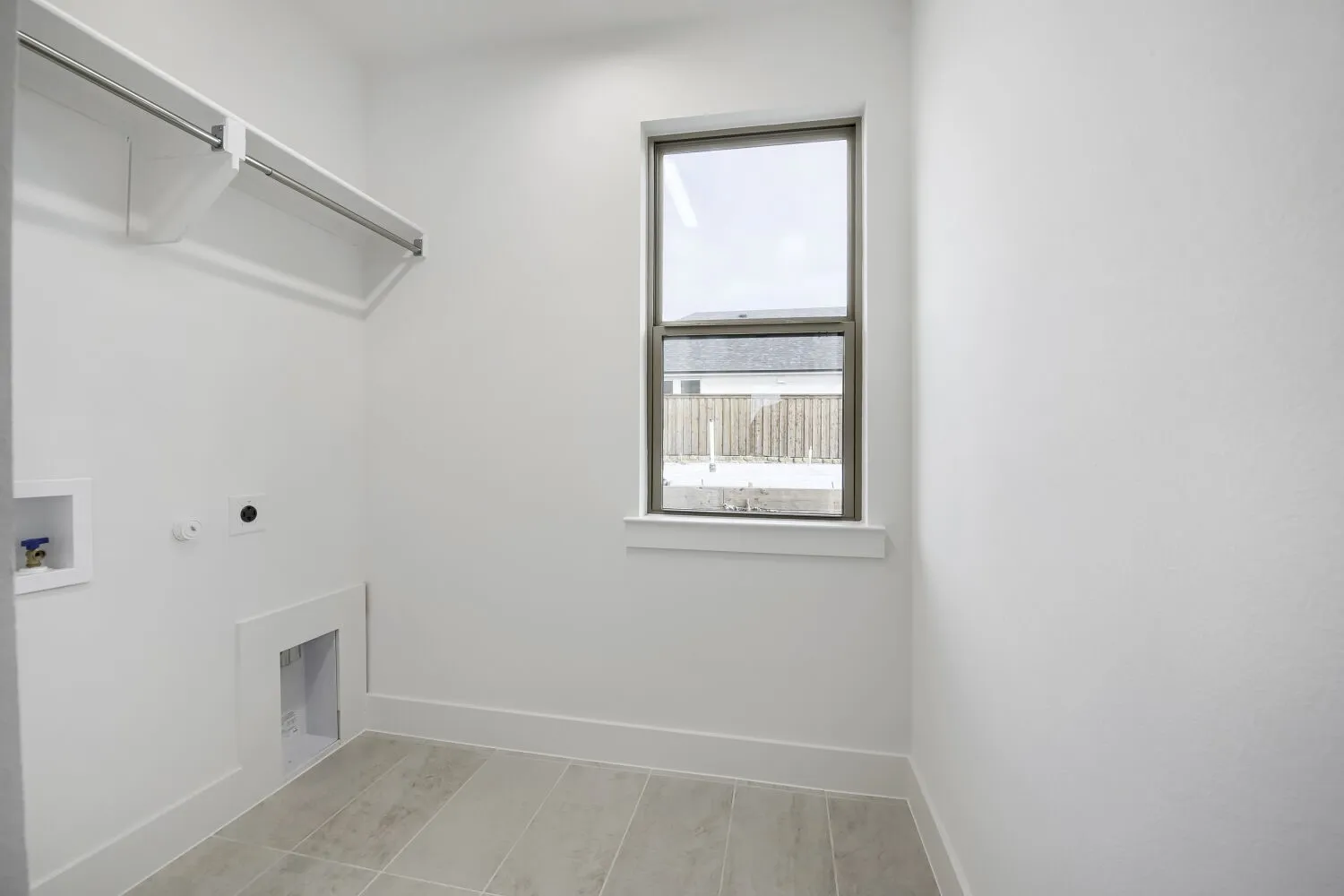 Laundry area featuring a single window, overhead shelving with a hanging rod, appliance hookups, and large format tile flooring