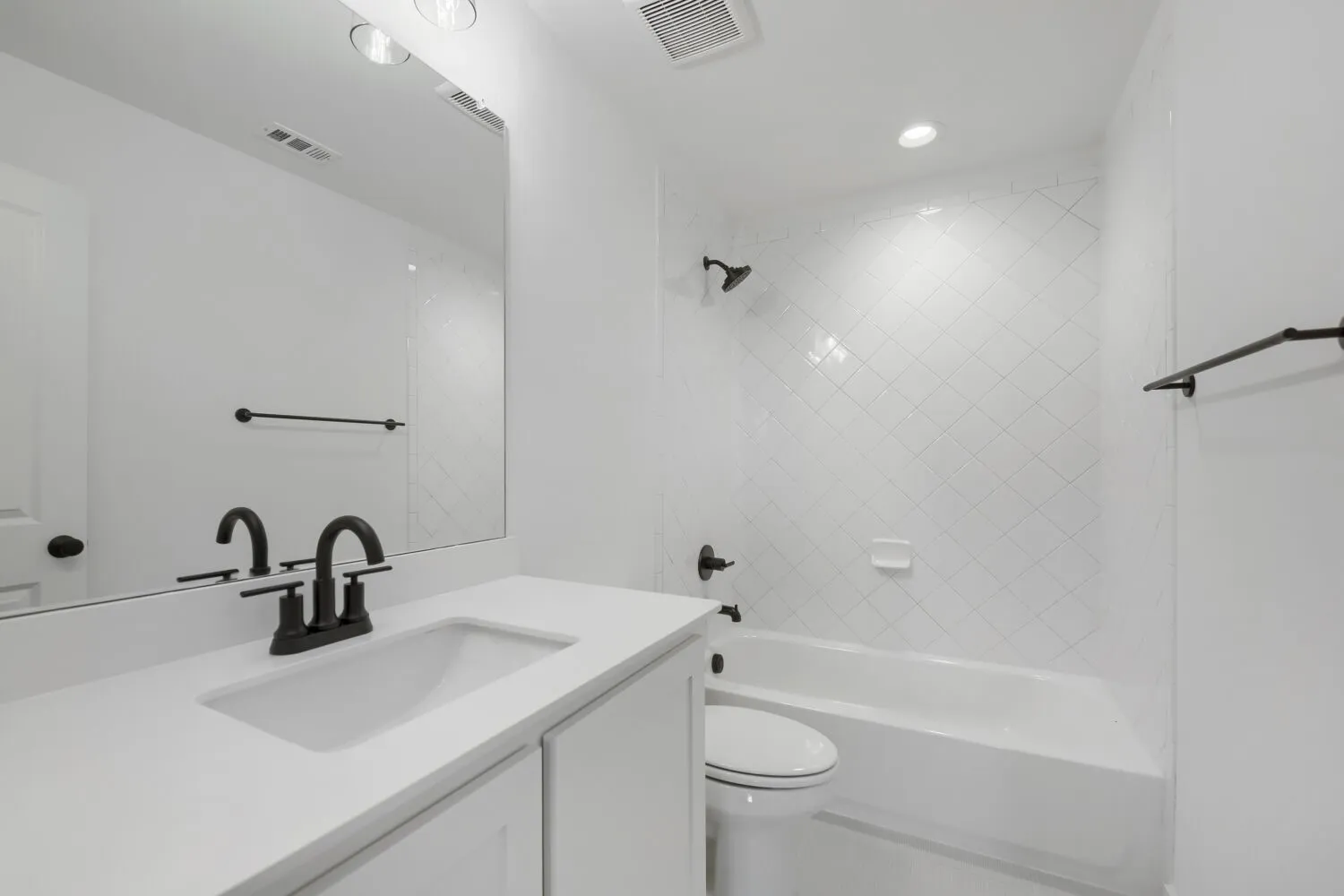 Bathroom featuring a white vanity with an integrated sink, matte black faucet, and a large wall mirror