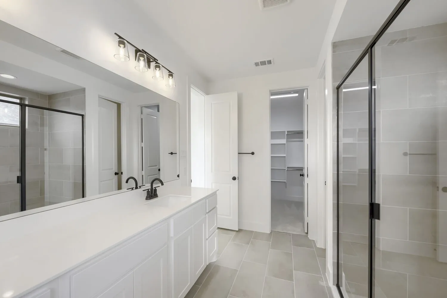 Spacious bathroom featuring a dual vanity with white cabinetry and a solid surface countertop
