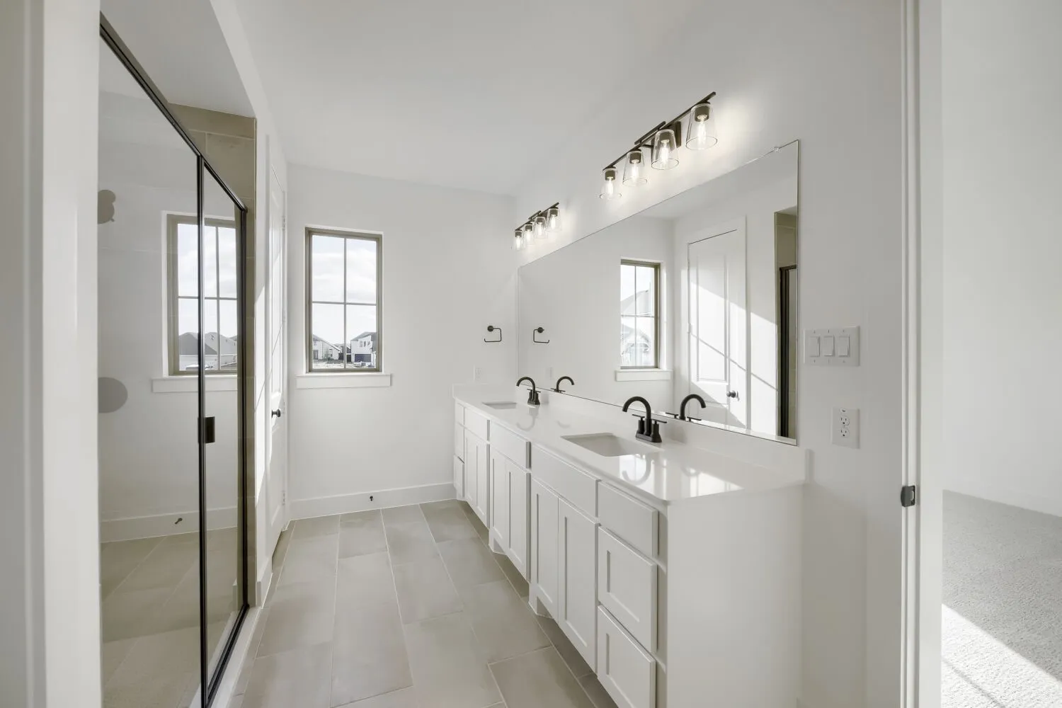 Bathroom featuring a dual vanity with white cabinetry, integrated sinks, and black fixtures