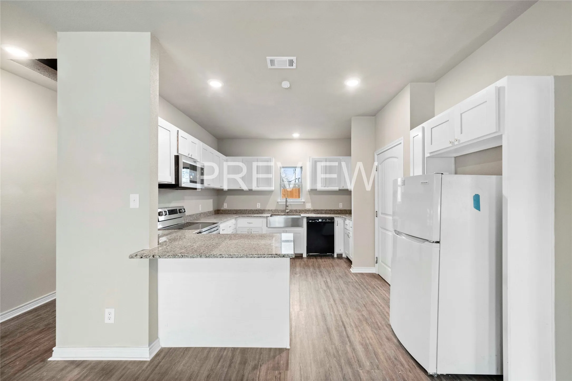 Spacious kitchen featuring white cabinetry, granite-finish countertops, wood-finish flooring, recessed lighting, and a breakfast bar