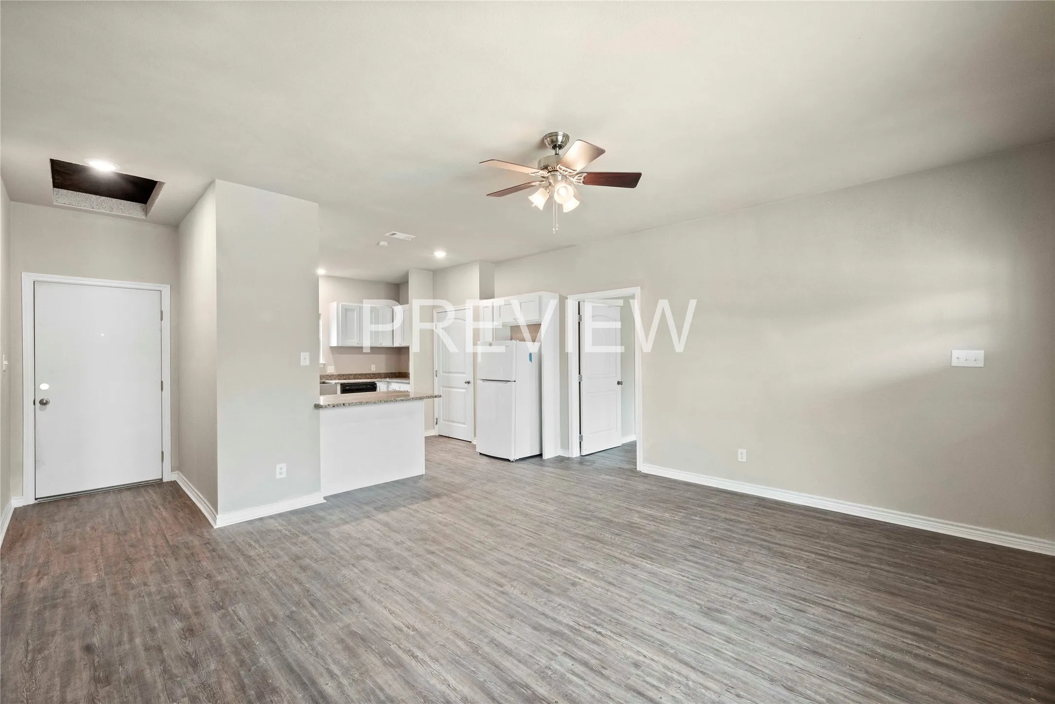 Open-concept living area featuring wood-finish flooring, a ceiling fan, and light gray wall tones