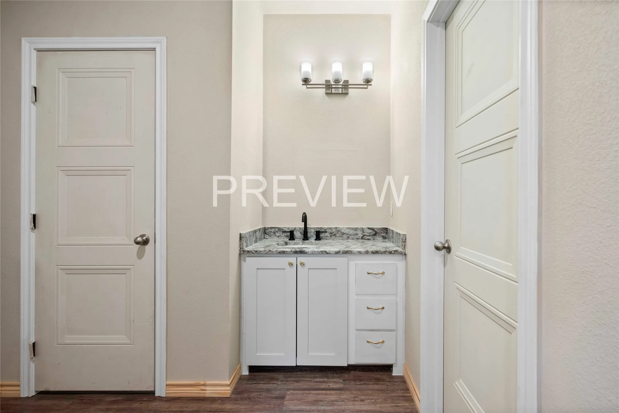 Wet bar featuring a granite-style countertop, undermount sink, matte black faucet, white cabinetry, and brushed nickel lighting
