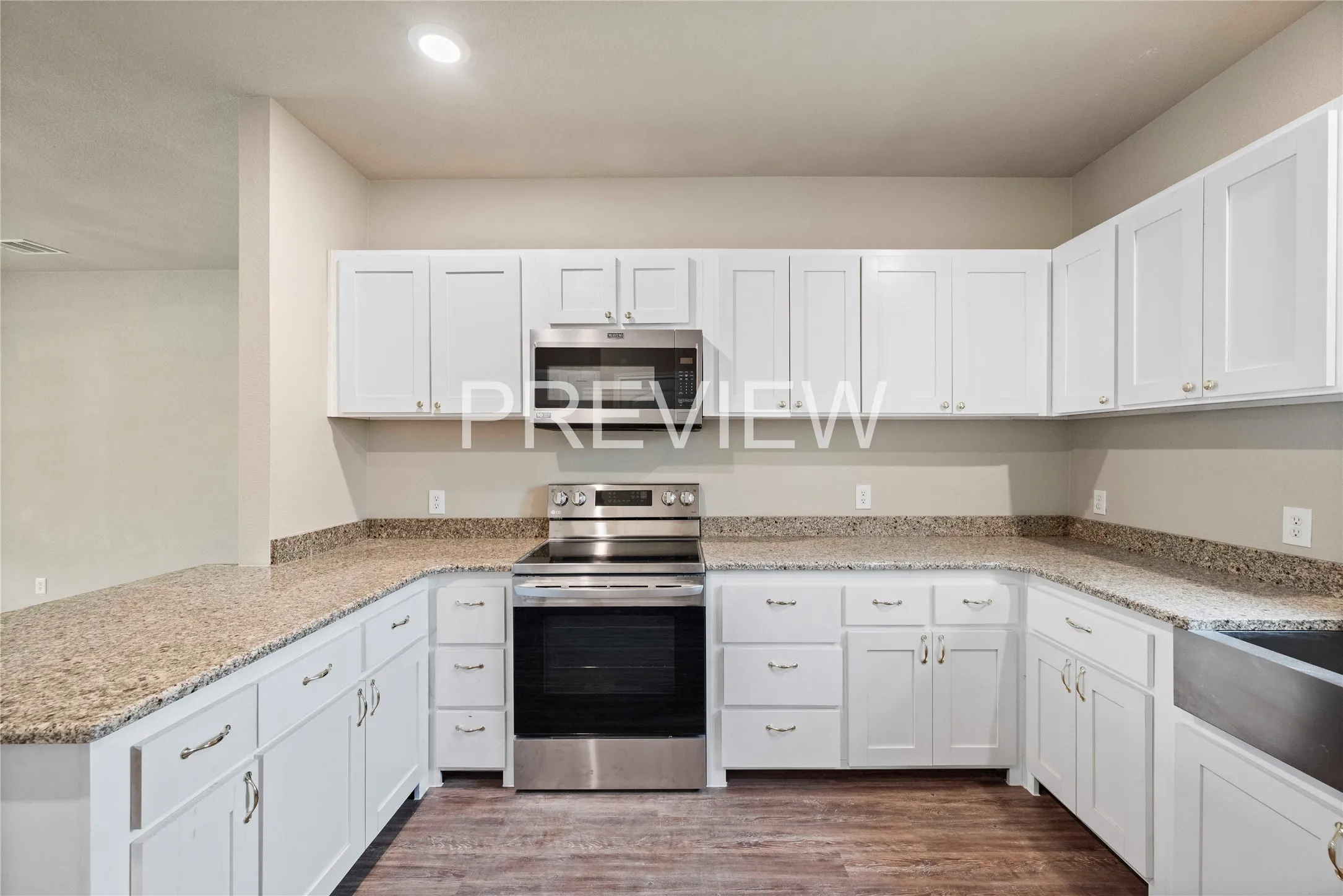 U-shaped kitchen featuring white shaker cabinetry, speckled countertops, stainless steel appliances, and wood-finish flooring