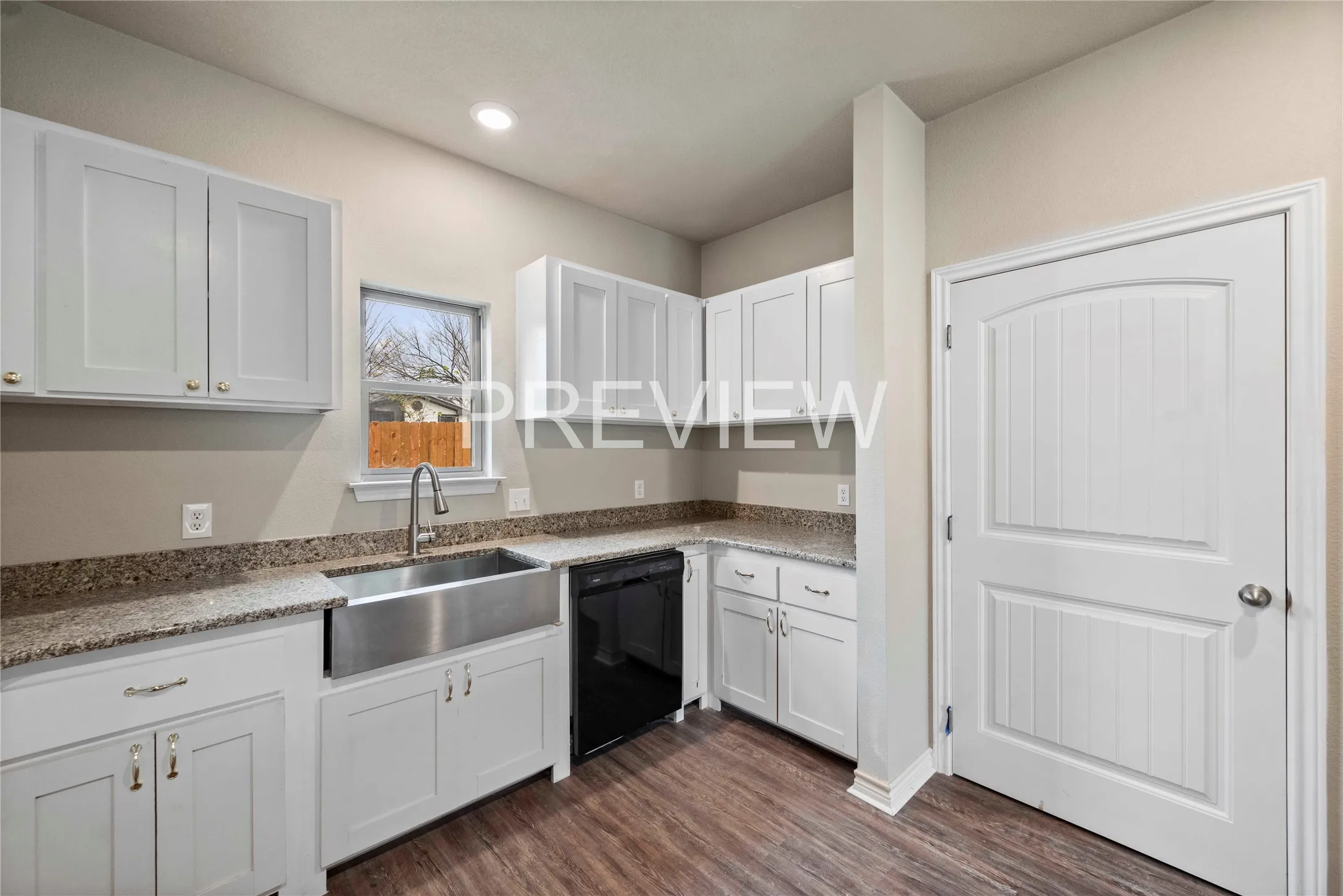 Kitchen featuring white shaker-style cabinetry, granite countertops, a stainless steel apron-front sink with a gooseneck faucet, a black dishwasher, and wood-finish flooring