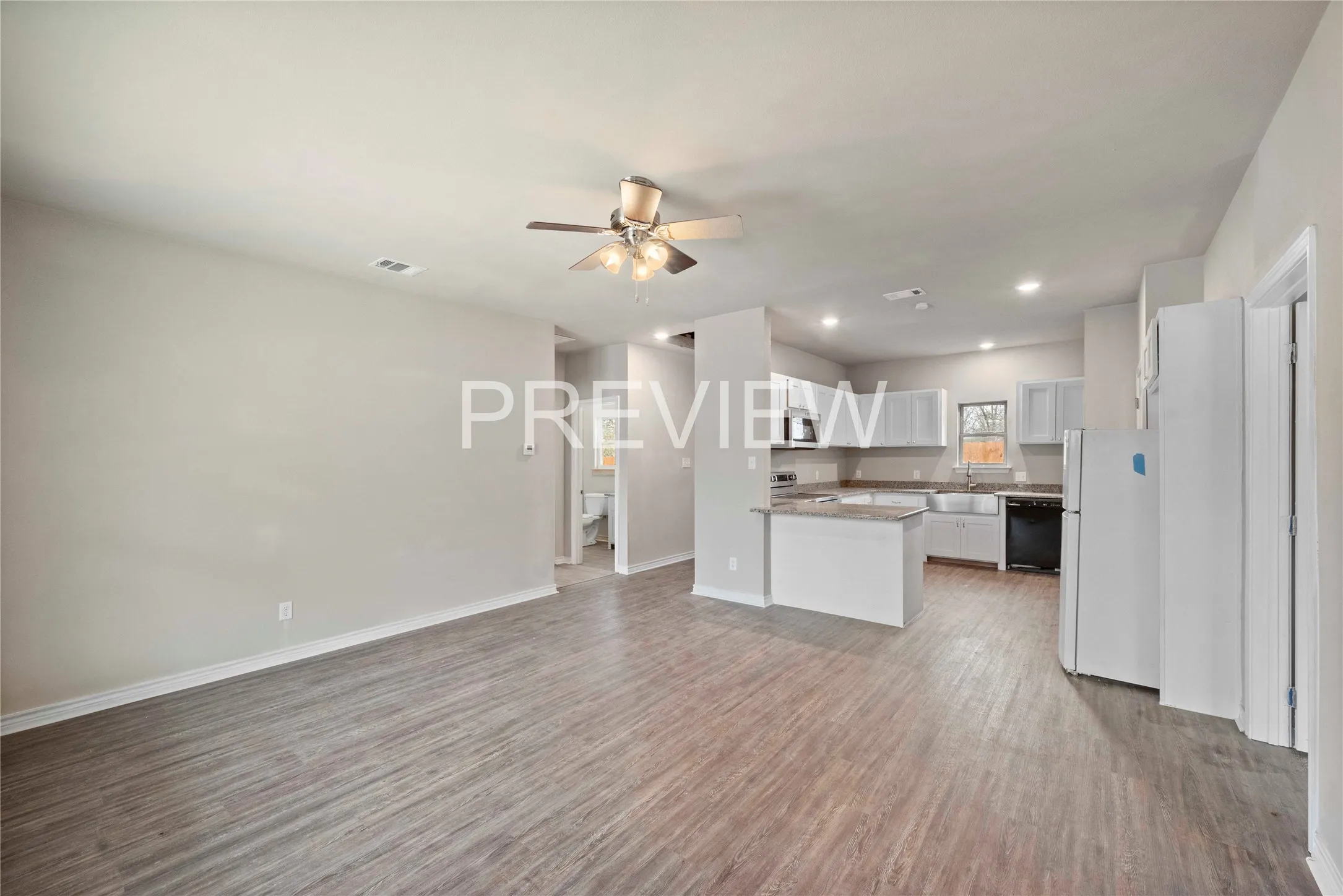 Spacious living area featuring wood-finish flooring, a ceiling fan, and recessed lighting