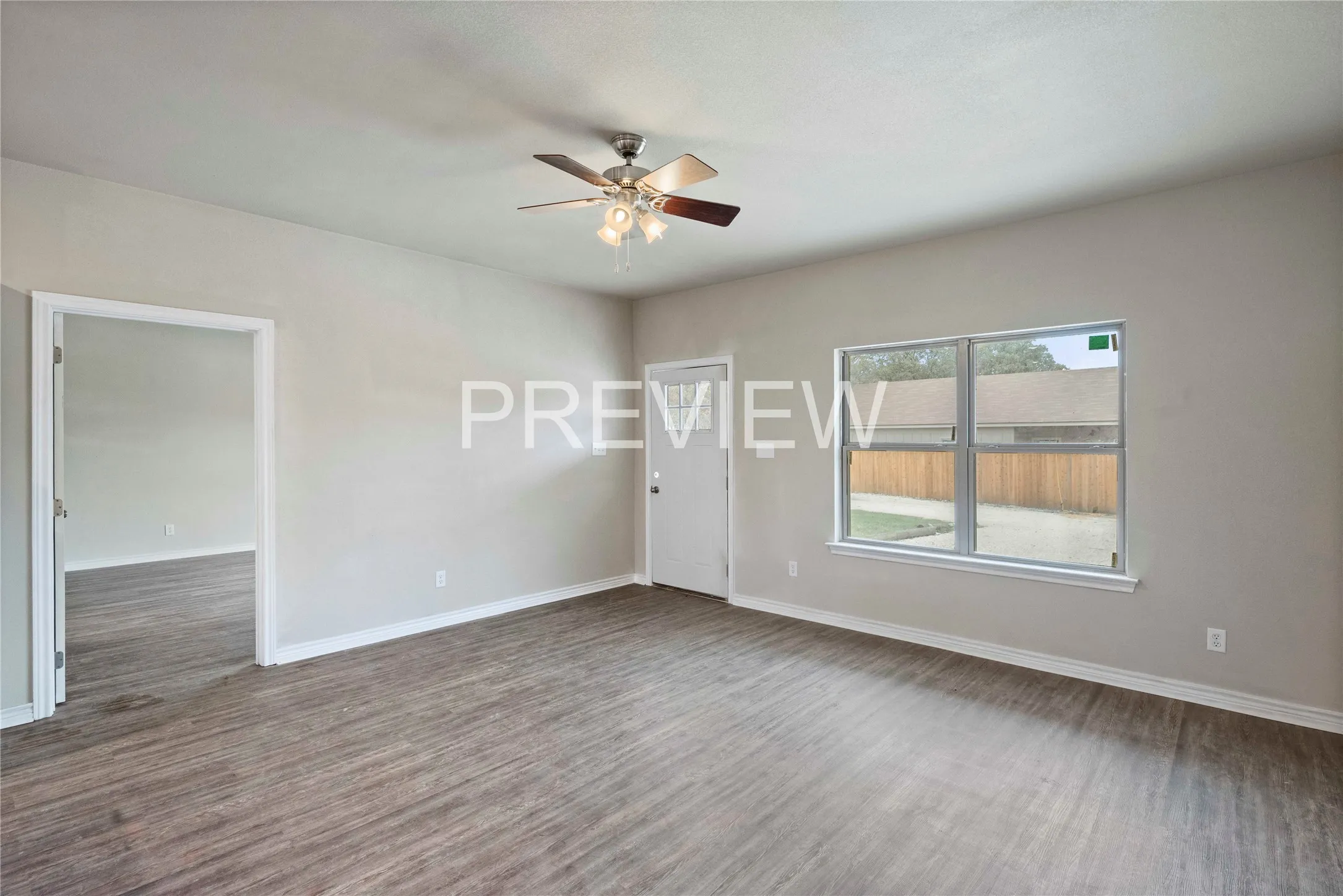 Spacious room featuring wood-finish flooring, light gray wall paint, and white baseboards