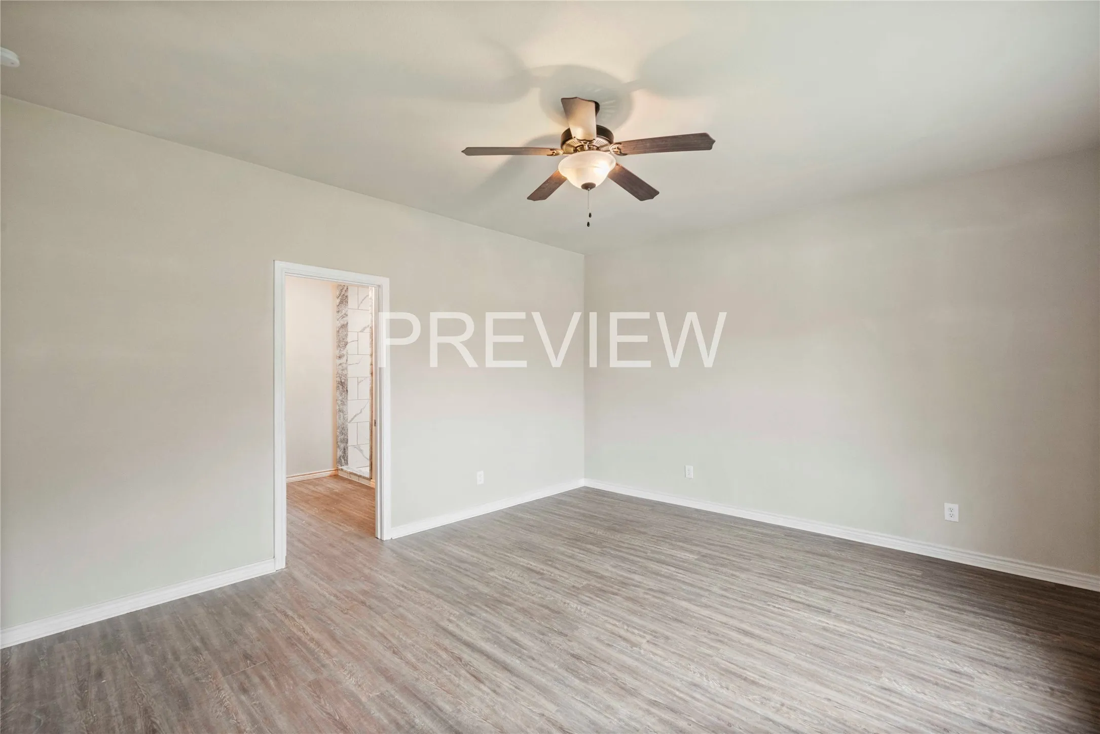 Spacious room featuring wood-finish flooring, a ceiling fan with integrated lighting, and a neutral wall palette