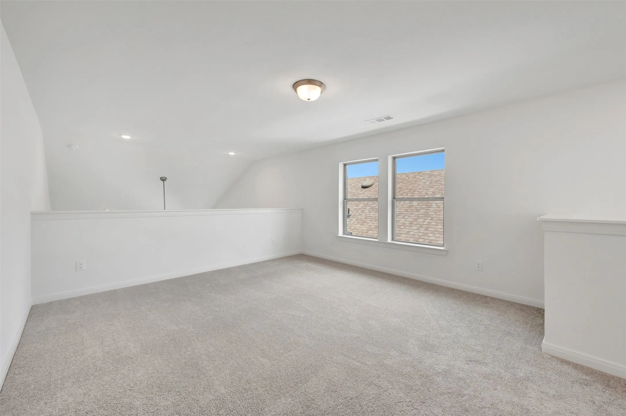 Carpeted loft area with two windows, recessed lighting, and a ceiling-mounted light fixture