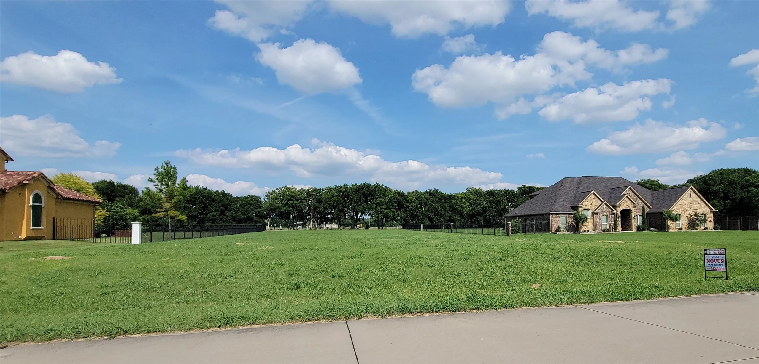 Expansive green lot with established landscaping and a paved road visible in the foreground