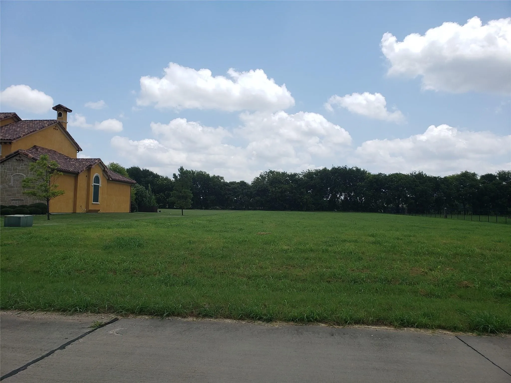 Expansive green lawn with a backdrop of mature trees