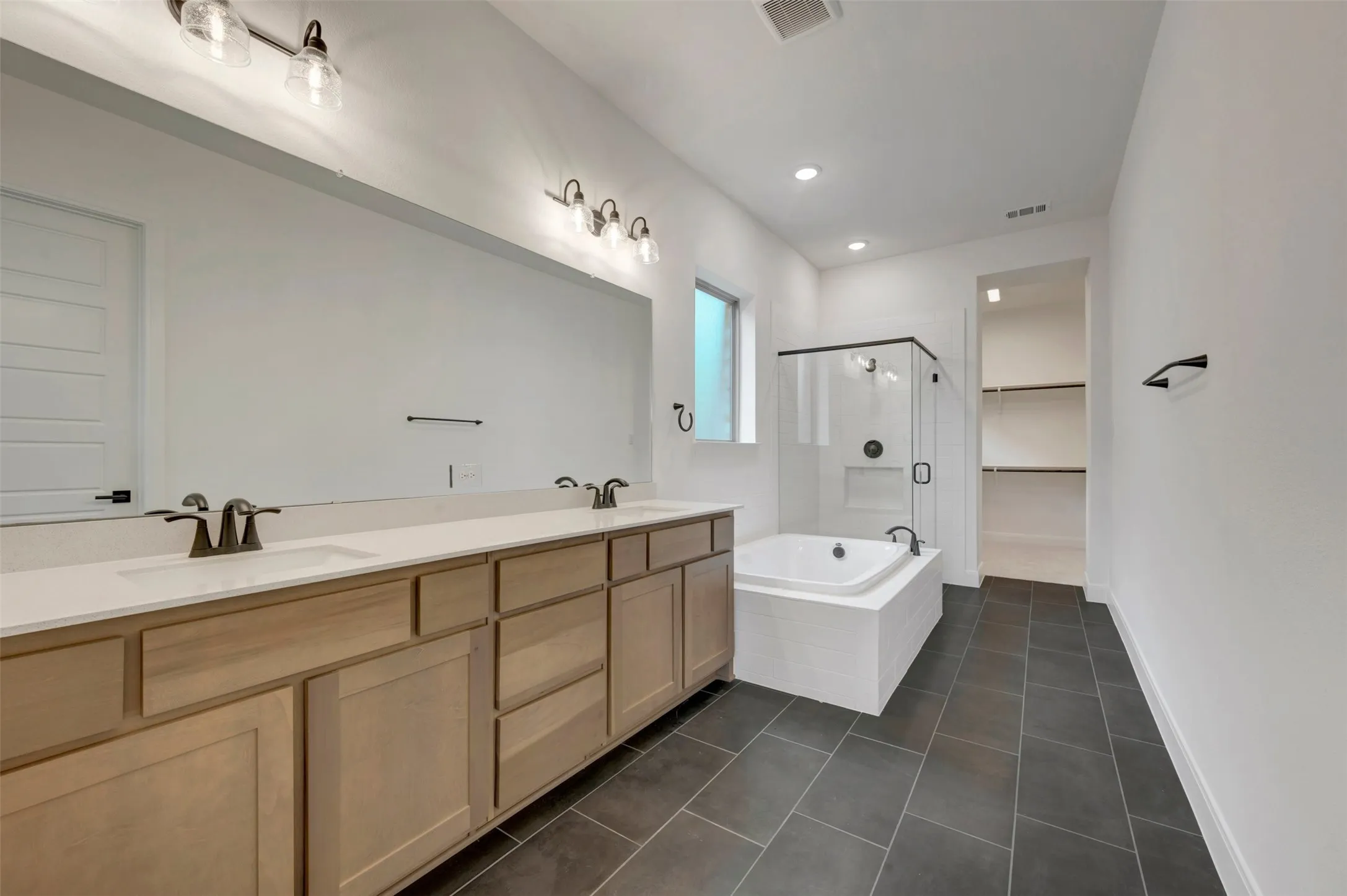 Double vanity with light wood-finish cabinetry and white countertops