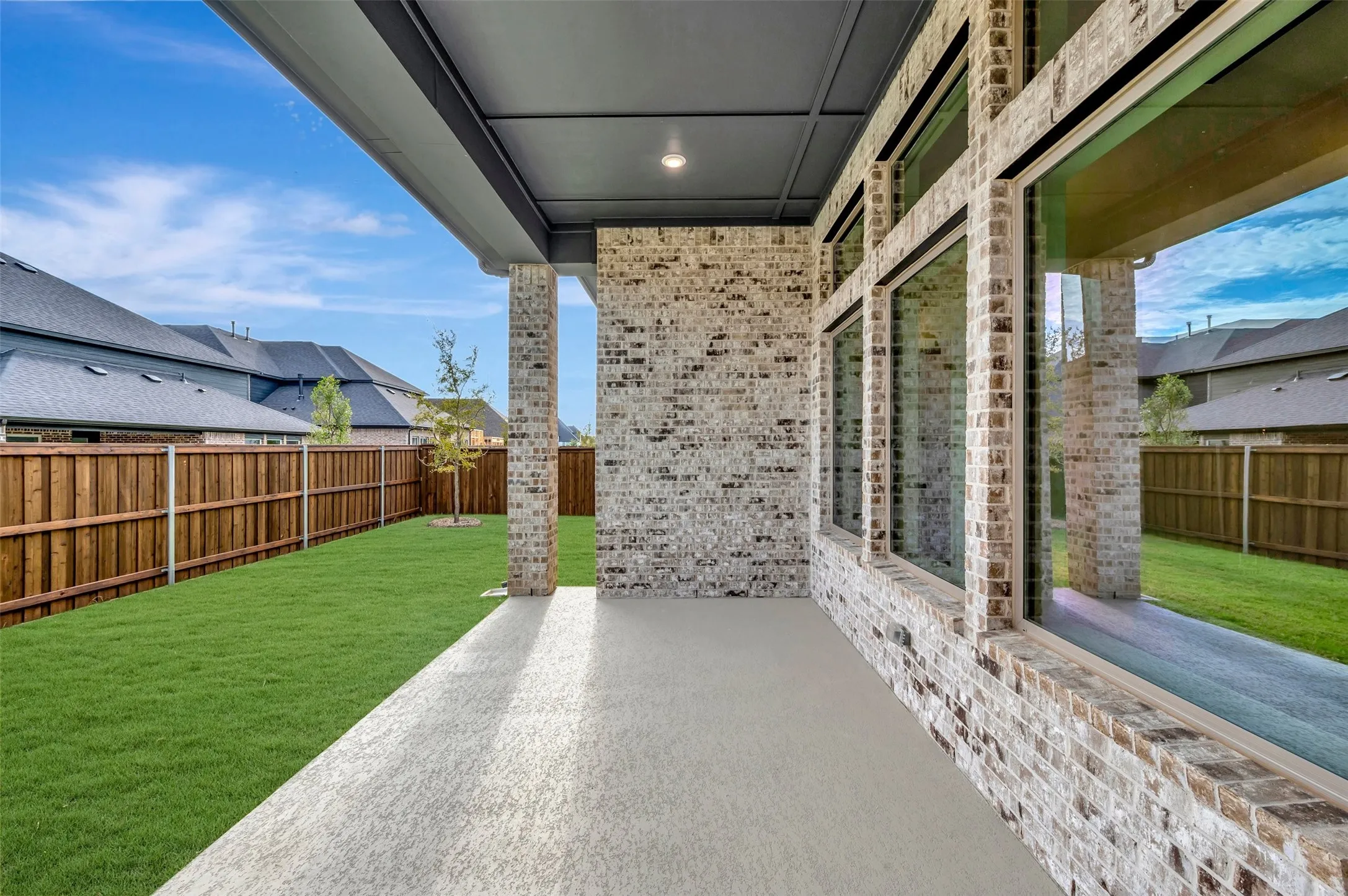 Covered patio with a concrete surface, extensive brick exterior, and large pane windows