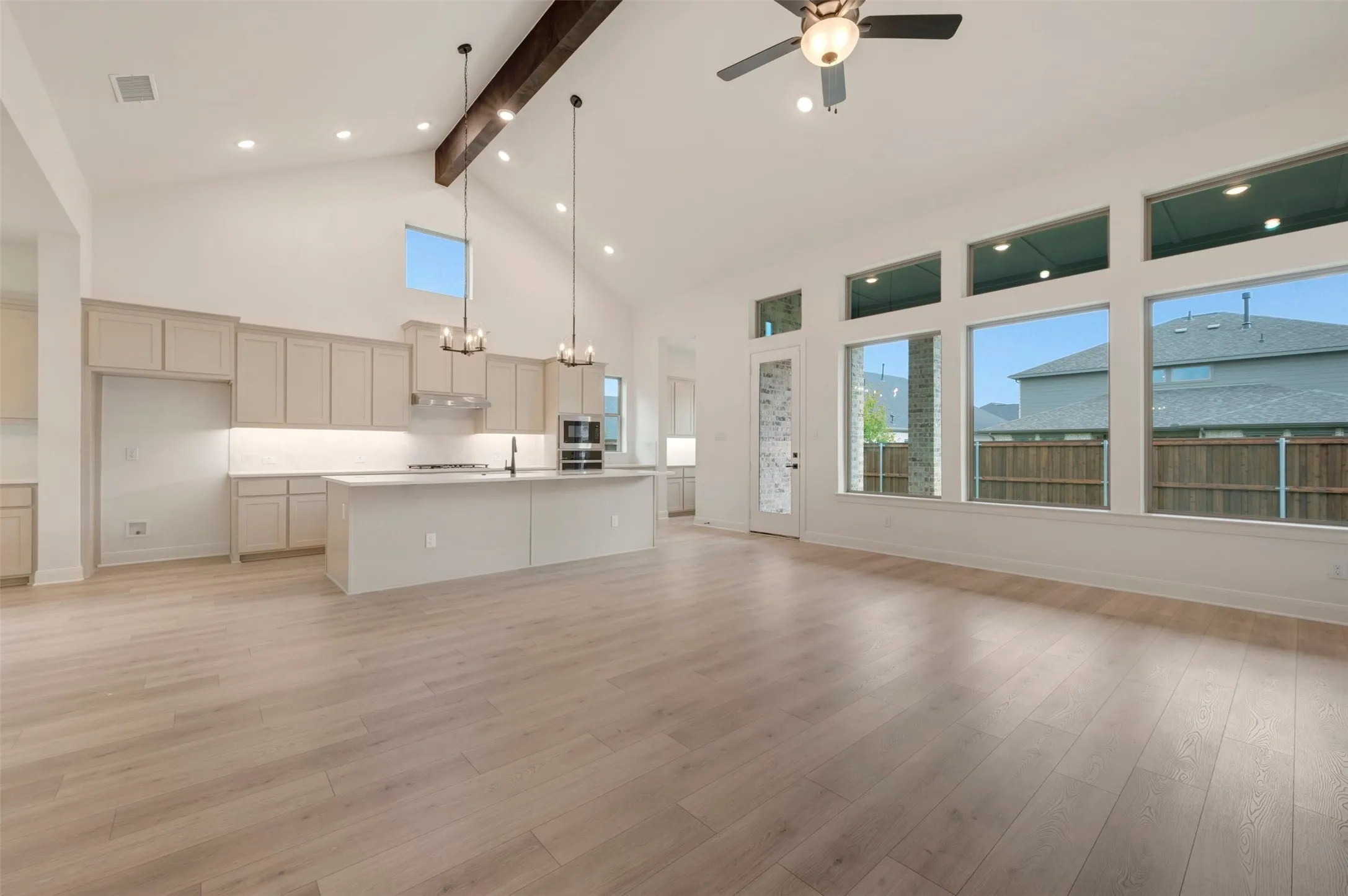 Expansive open-concept space featuring wood-finish flooring, a vaulted ceiling with an exposed beam, and recessed lighting