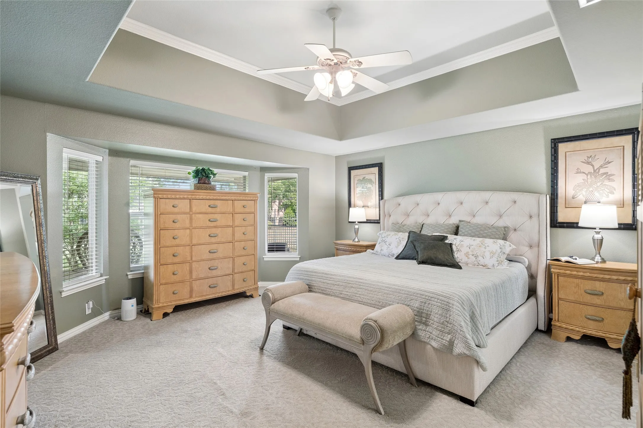 Oversized primary bedroom with tray ceiling and views to landscaped backyard