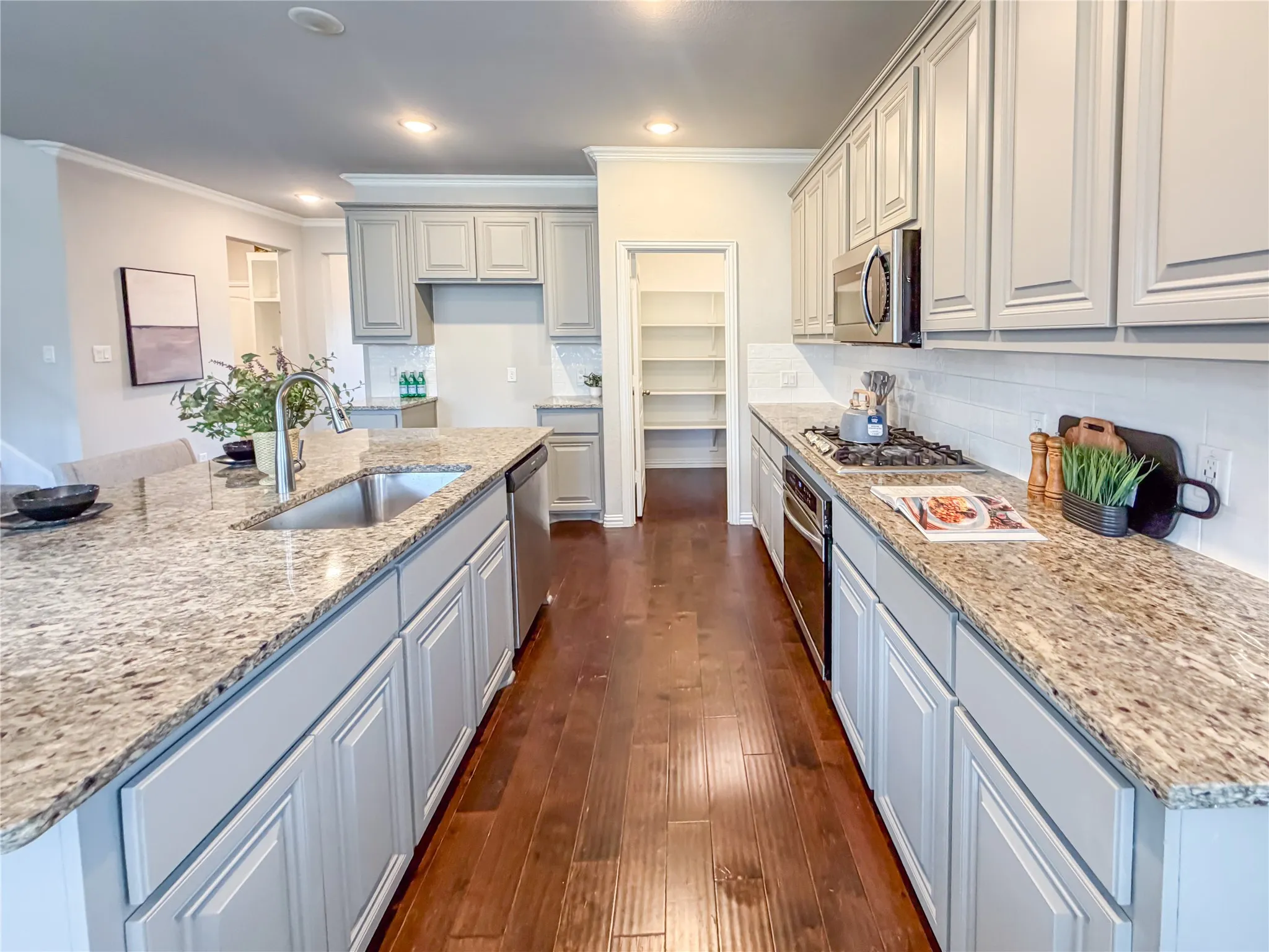 Kitchen featuring extensive light gray cabinetry, granite countertops, stainless steel appliances, a tile backsplash, and wood-finish flooring