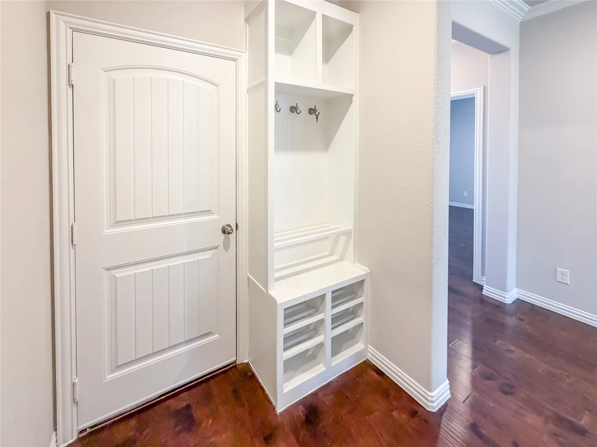 Built-in mudroom station featuring upper cubbies, coat hooks, bench seating, and lower shoe storage