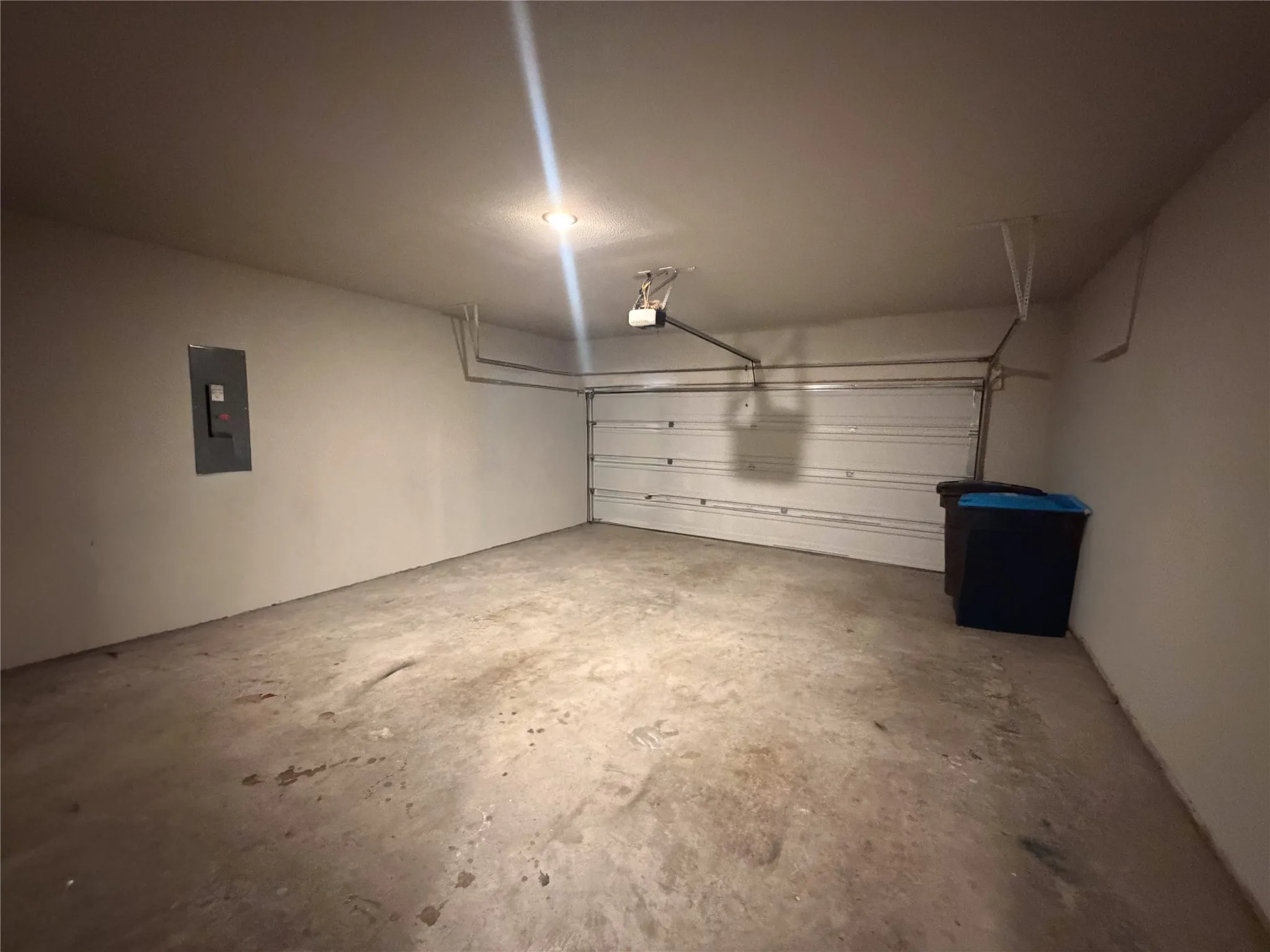 Single-bay garage featuring a concrete floor and white painted walls