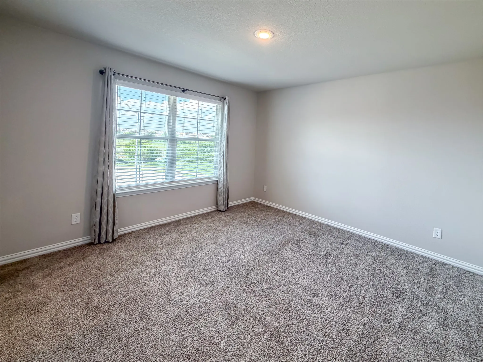 Carpeted room with a recessed ceiling light, light-toned walls, and white baseboards
