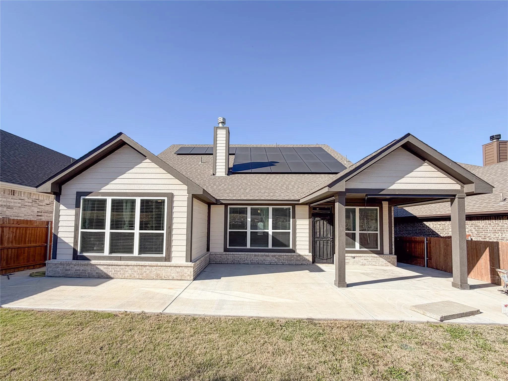 Rear exterior featuring a covered patio, multiple windows, and a concrete patio
