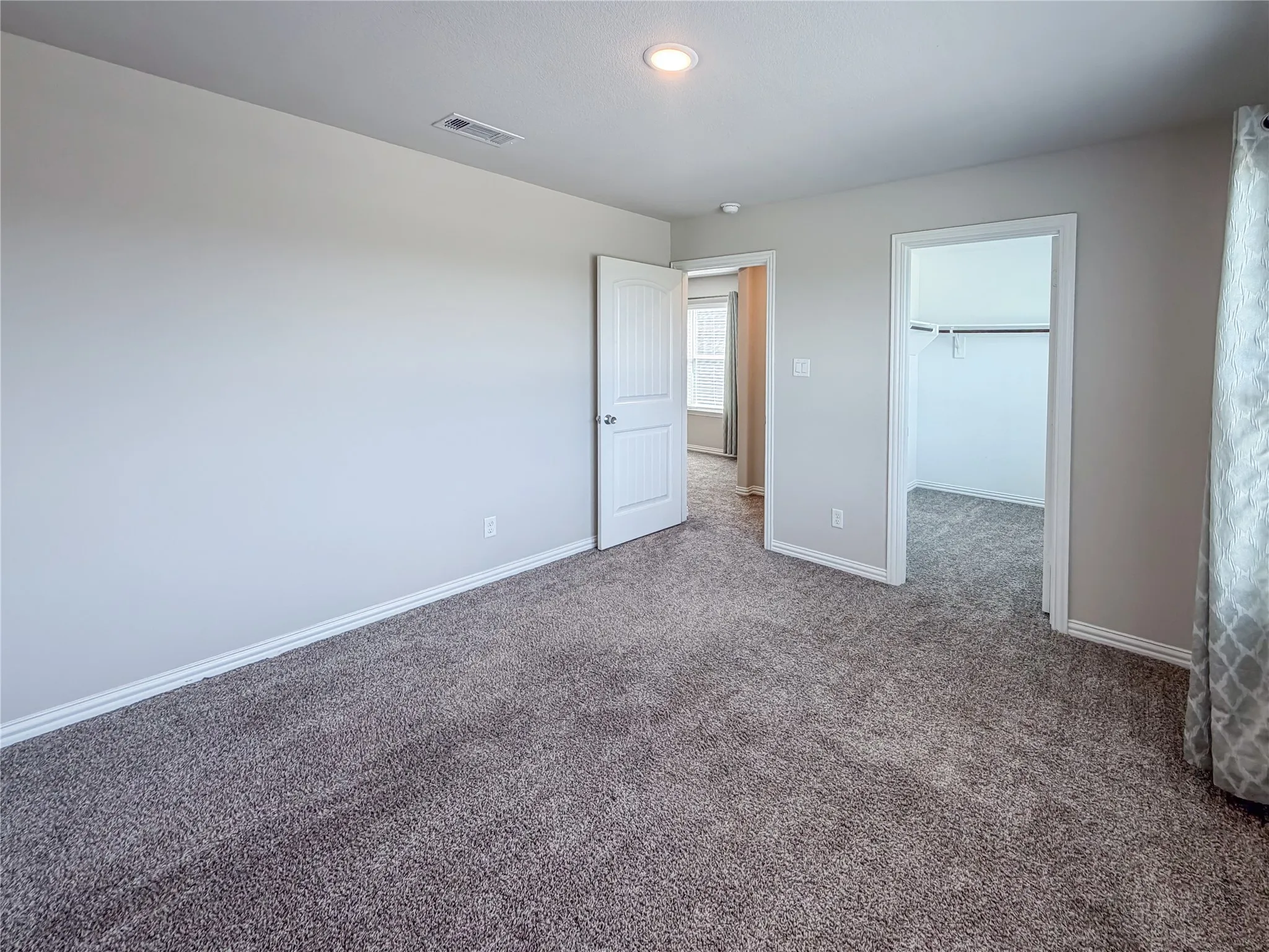 Carpeted room featuring light gray walls, white trim, recessed ceiling lighting, and a closet with a built-in hanging rod