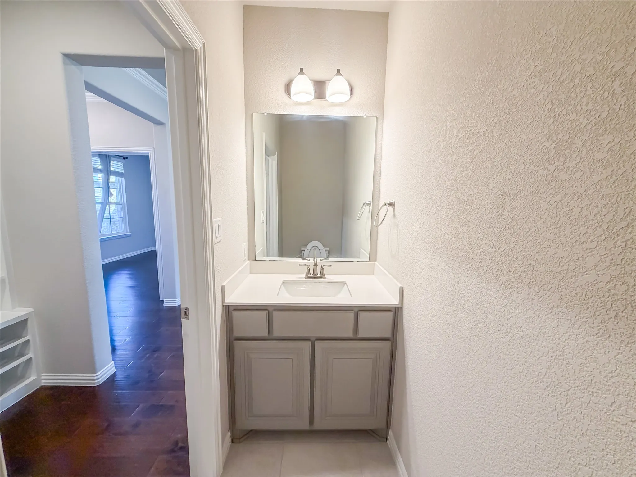 Compact vanity featuring a rectangular undermount sink and a light-colored solid surface countertop