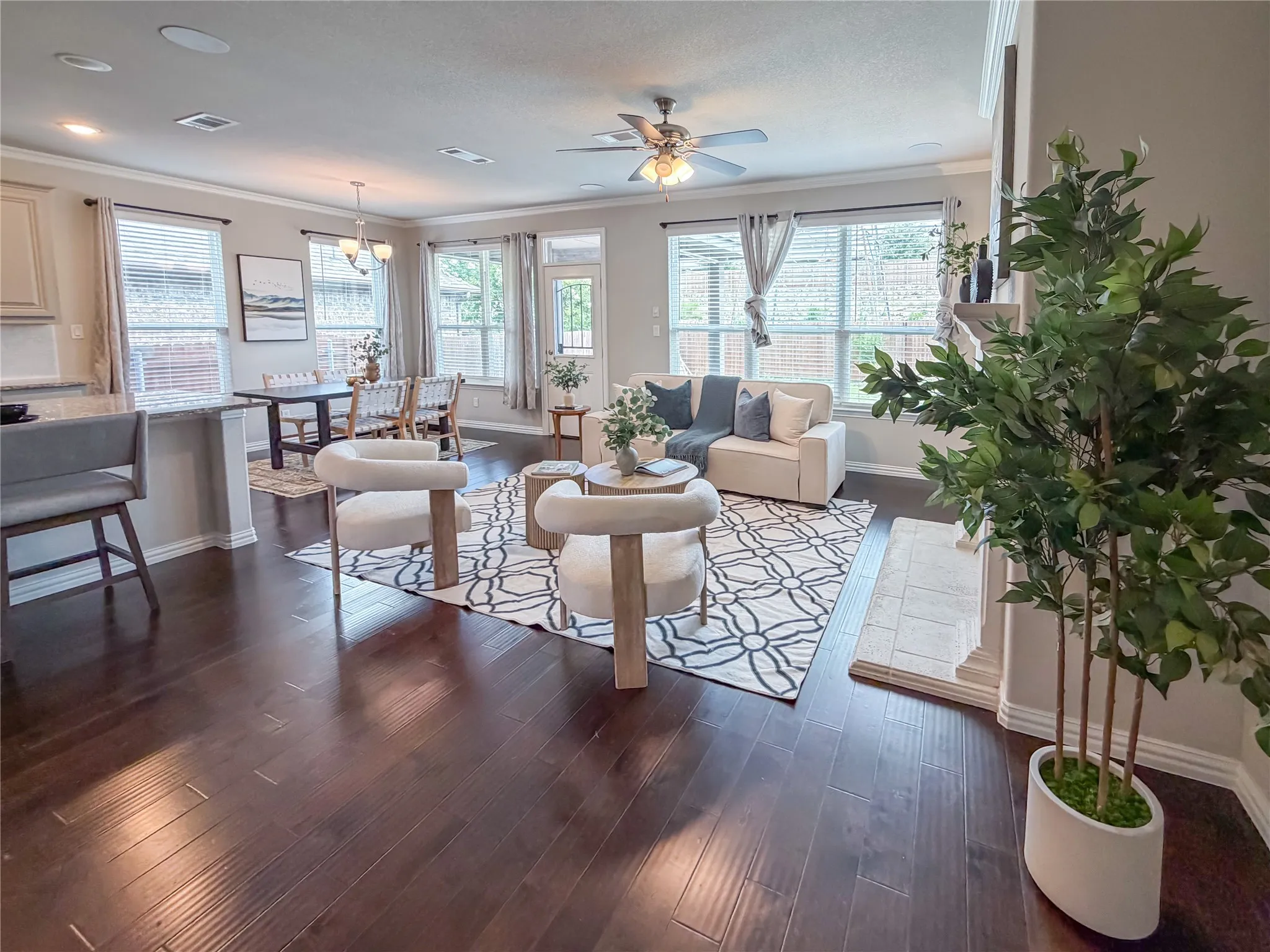 Expansive living area featuring rich wood-finish flooring, a decorative fireplace, and crown molding