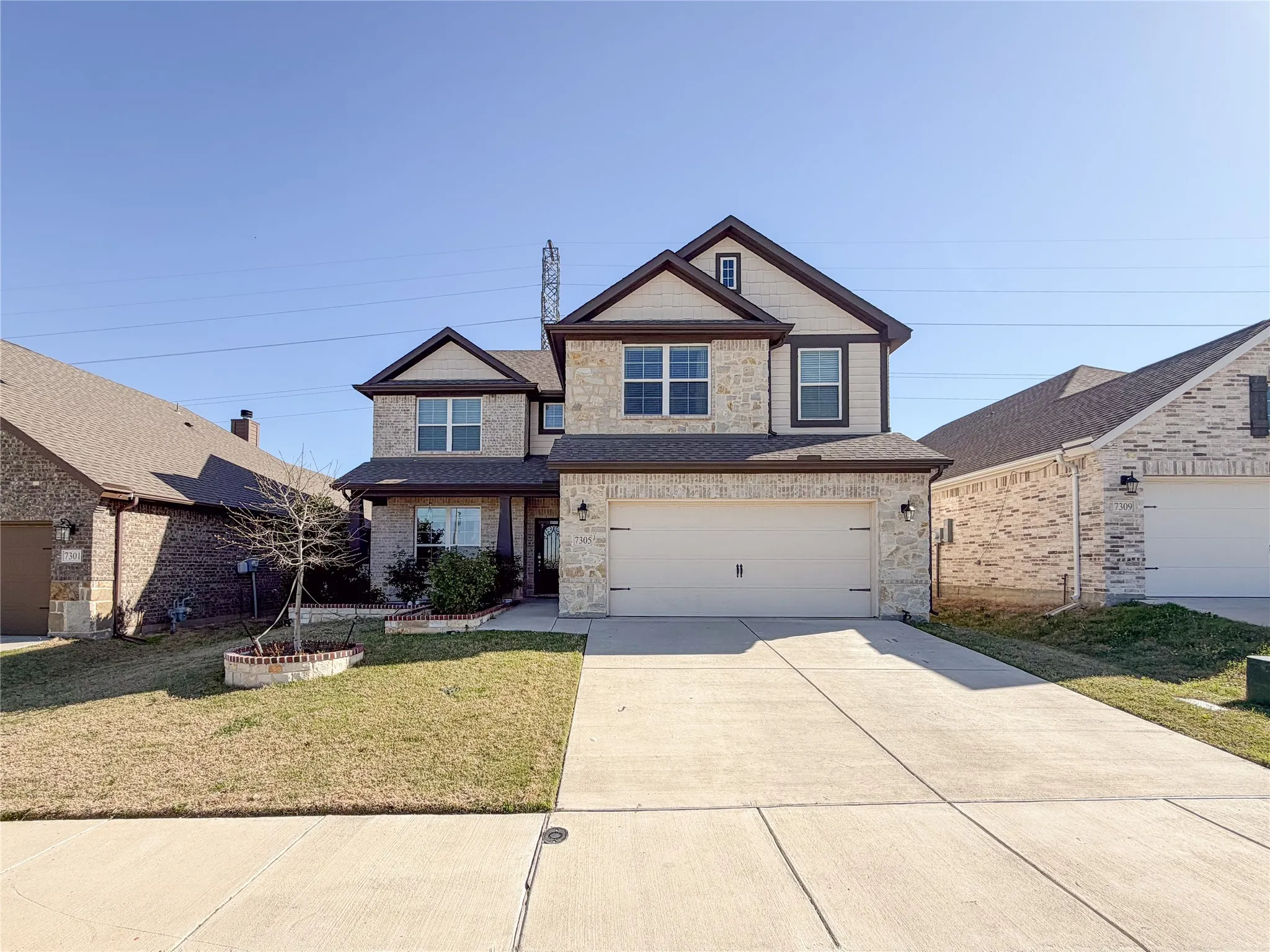 Two-story residence featuring a stone and siding facade, a two-car garage, and a concrete driveway