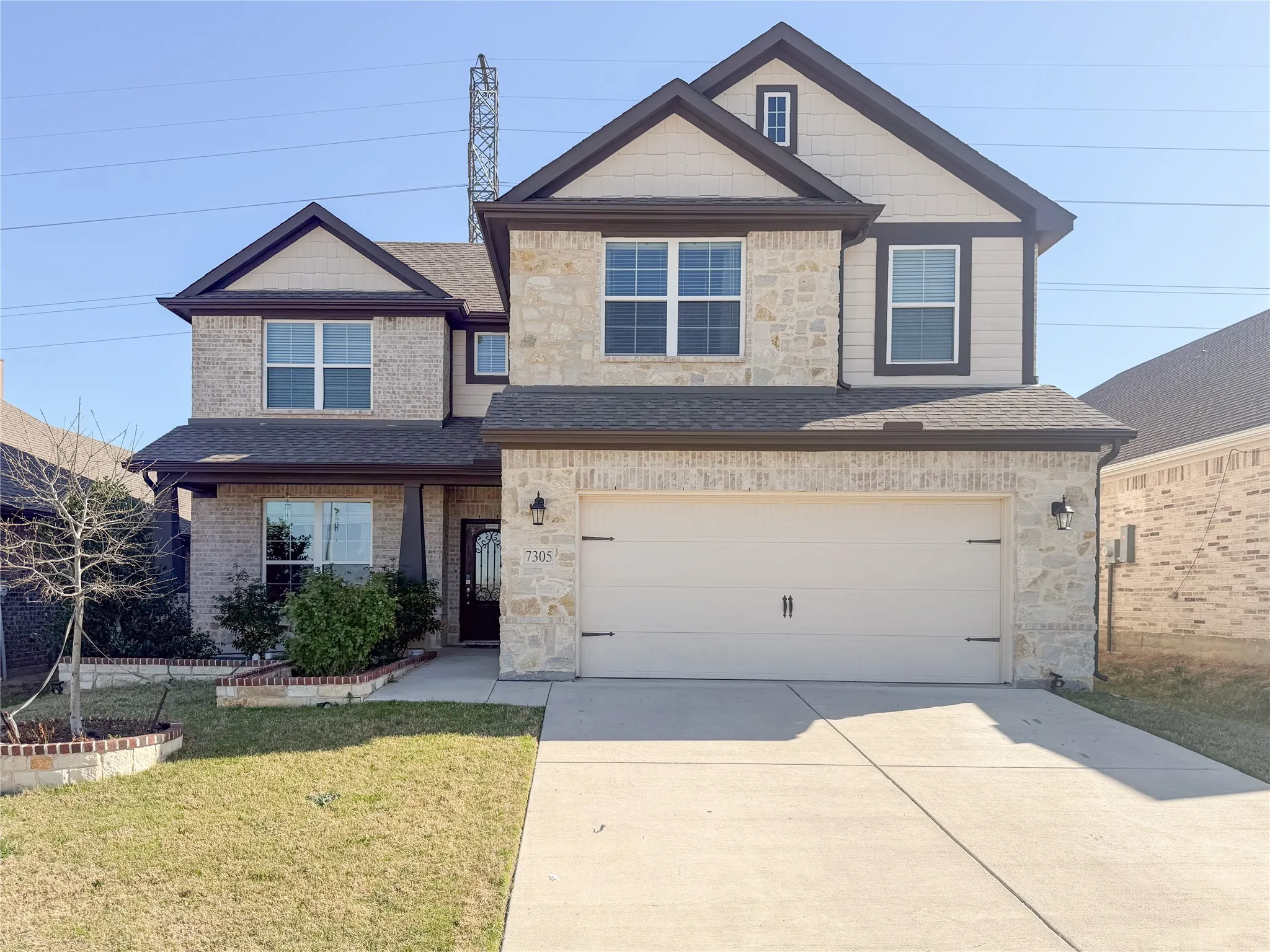 Two-story home featuring a stone and siding exterior with dark trim