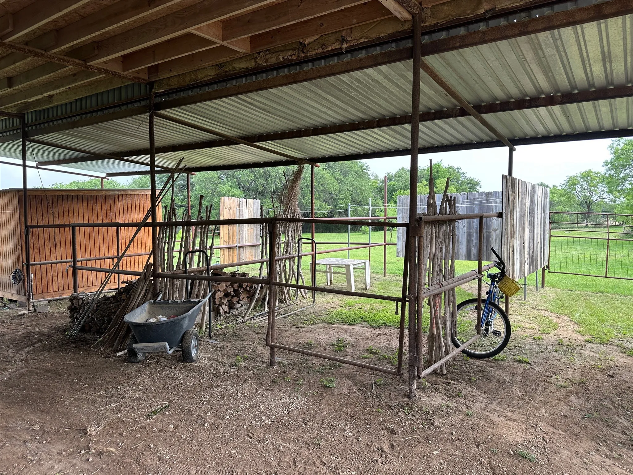 Open-air shed structure featuring metal roofing and exposed wood beams