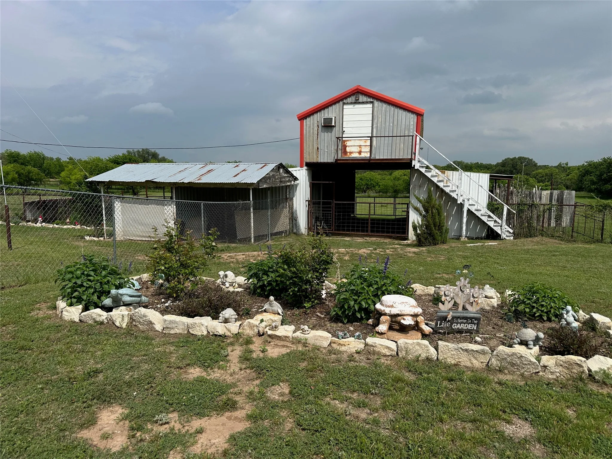 Outbuilding with metal siding and a red roof, featuring an external staircase and an elevated platform