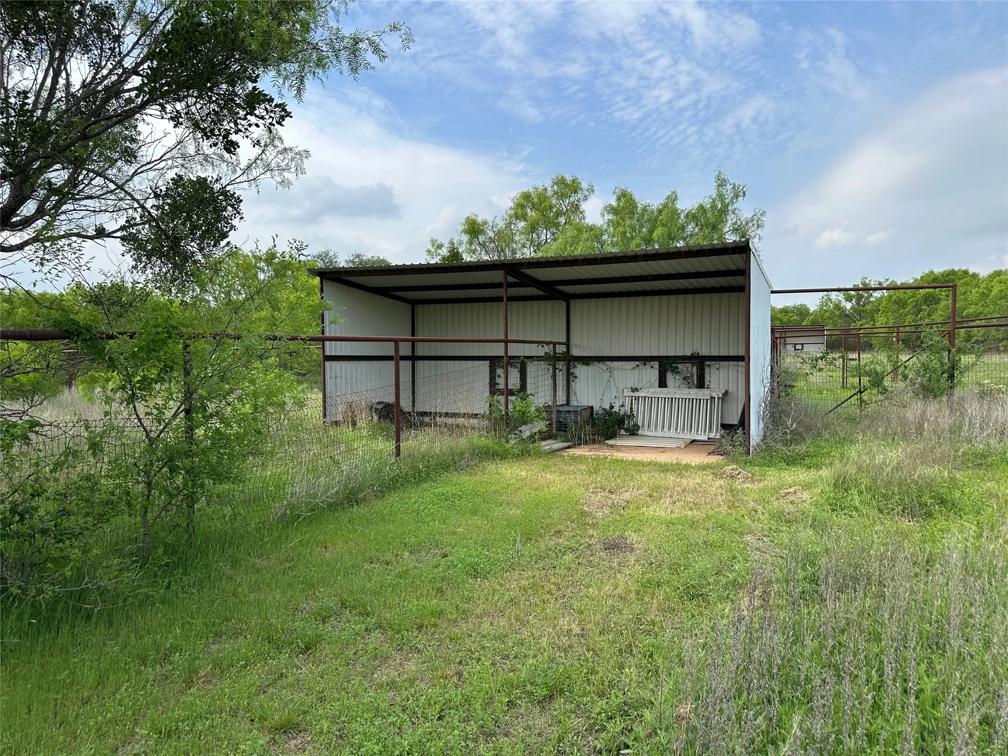 Open-sided metal structure featuring a corrugated roof and white paneling