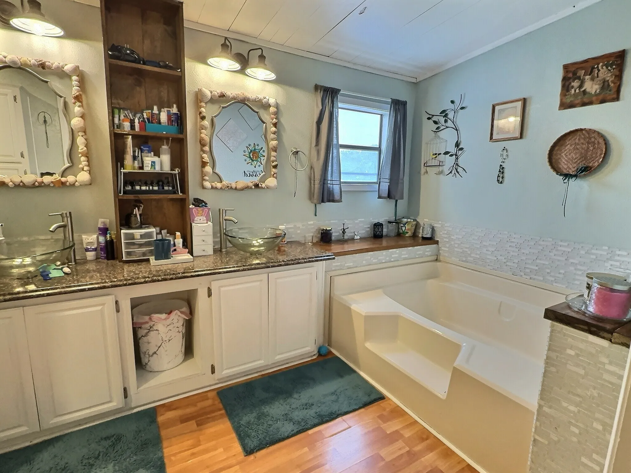Bathroom with double vanity featuring glass vessel sinks, stone-finish countertops, and under-cabinet storage