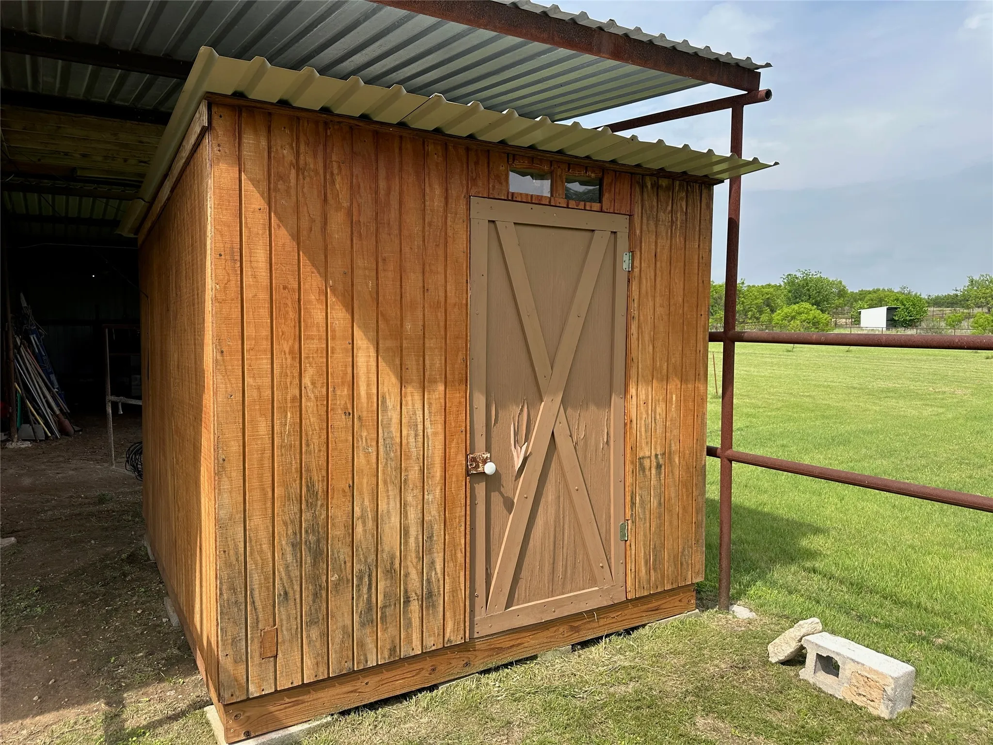 Wood-sided outbuilding featuring a corrugated metal roof and a barn-style door