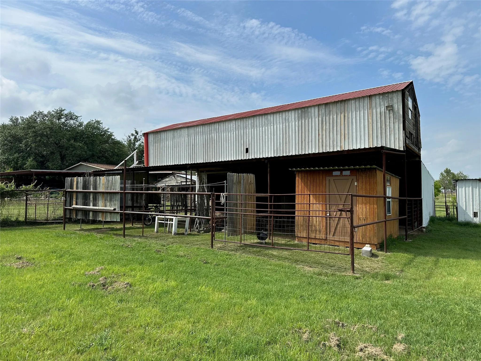 Two-story barn structure with a red metal roof and corrugated metal siding