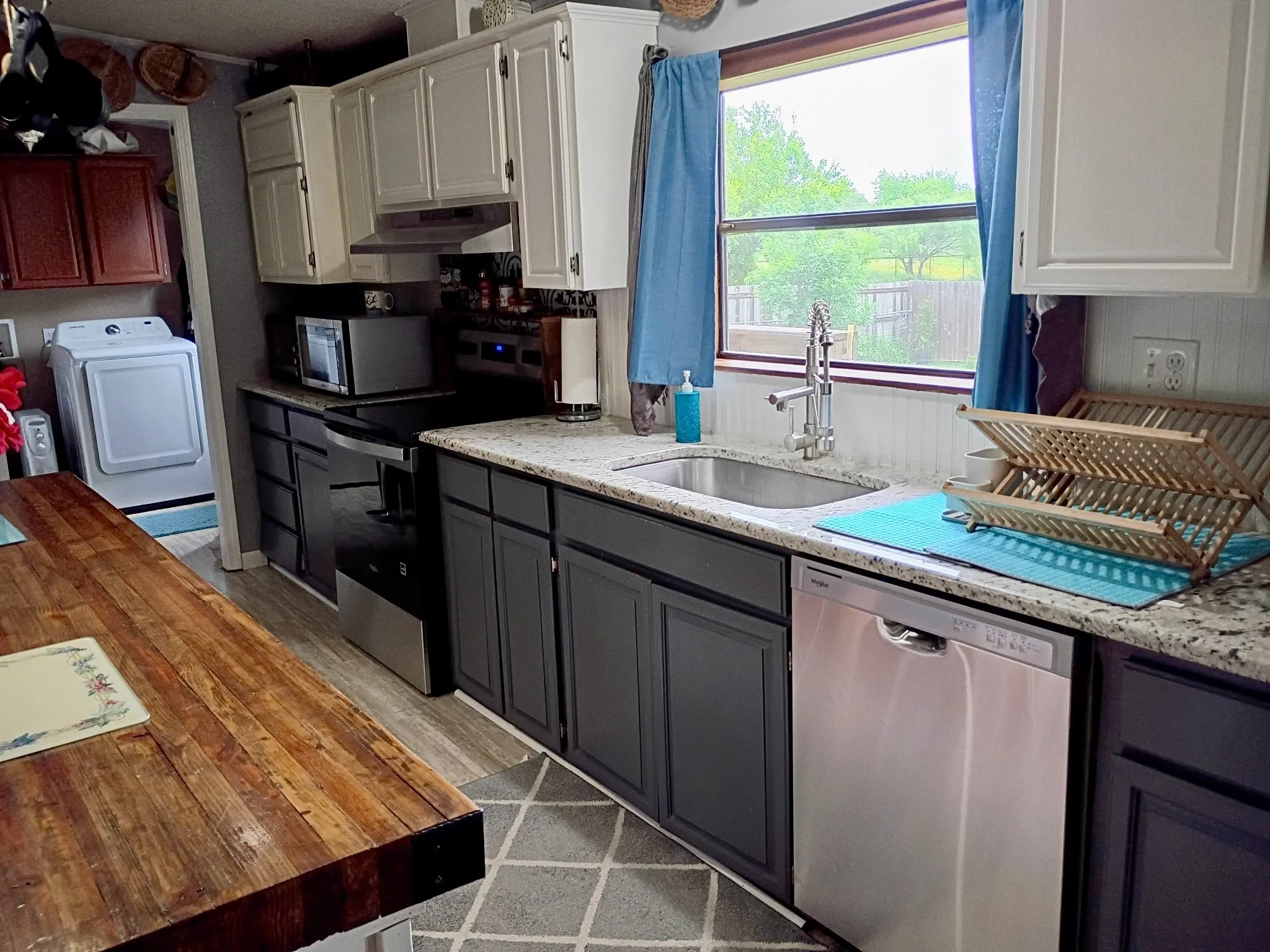 Kitchen featuring a stainless steel sink, a stainless steel dishwasher, a stainless steel range, and two-tone cabinetry with light upper cabinets and dark lower cabinets