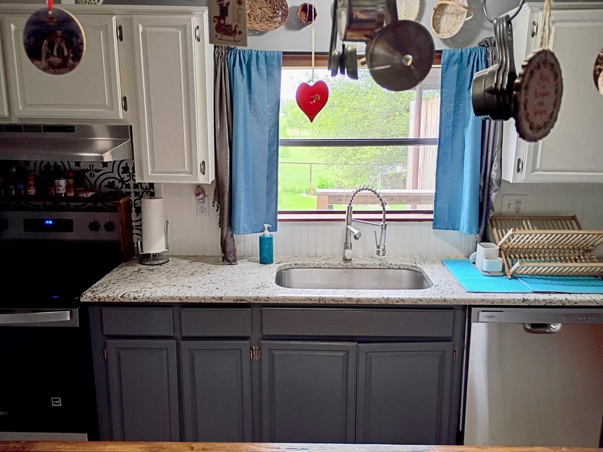 Kitchen featuring a stainless steel sink with a gooseneck faucet, light-toned countertop, and white upper cabinetry