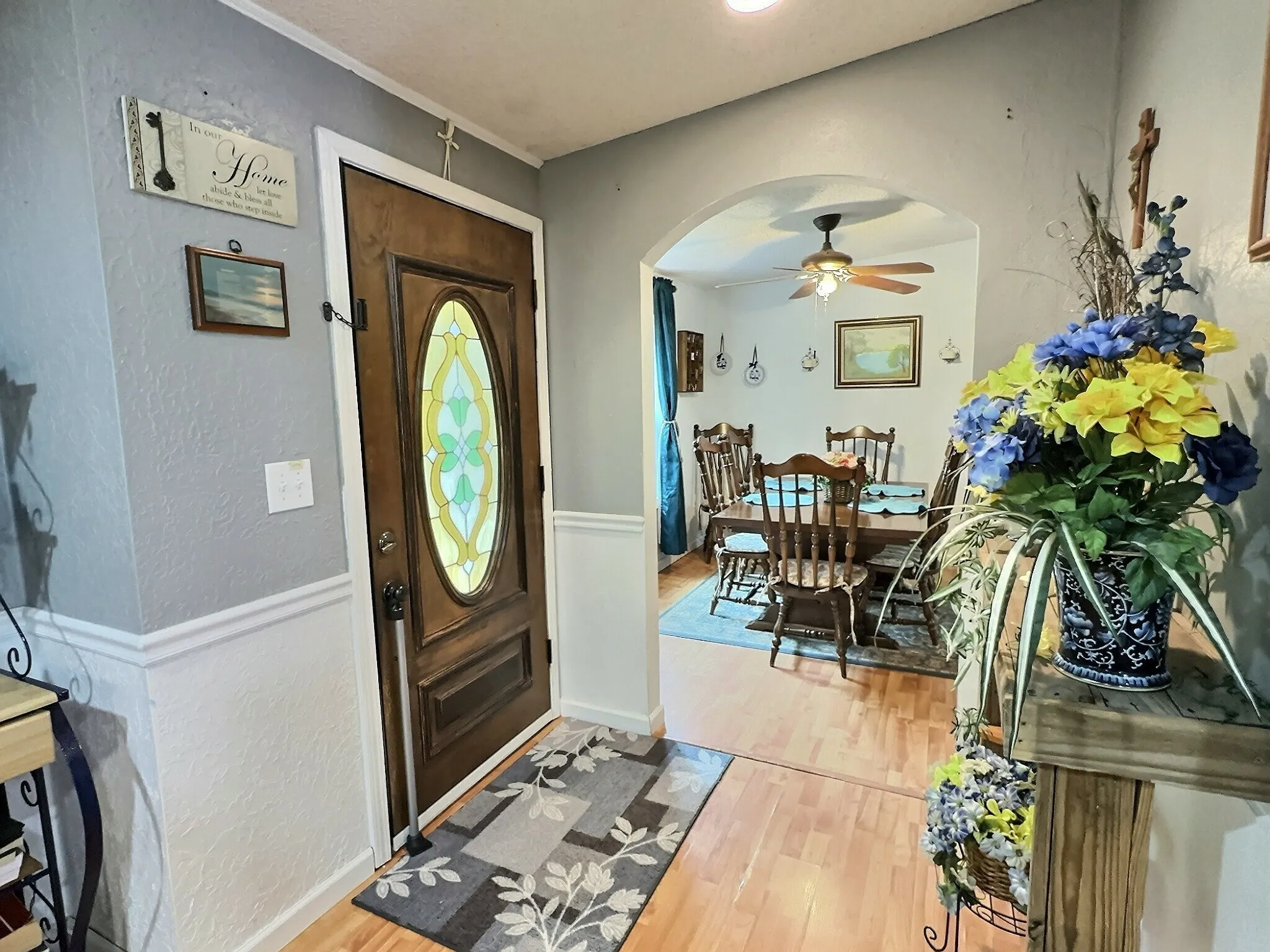 Entryway featuring a wood-panel door with decorative glass inserts, half-wall wainscoting, and wood-finish flooring