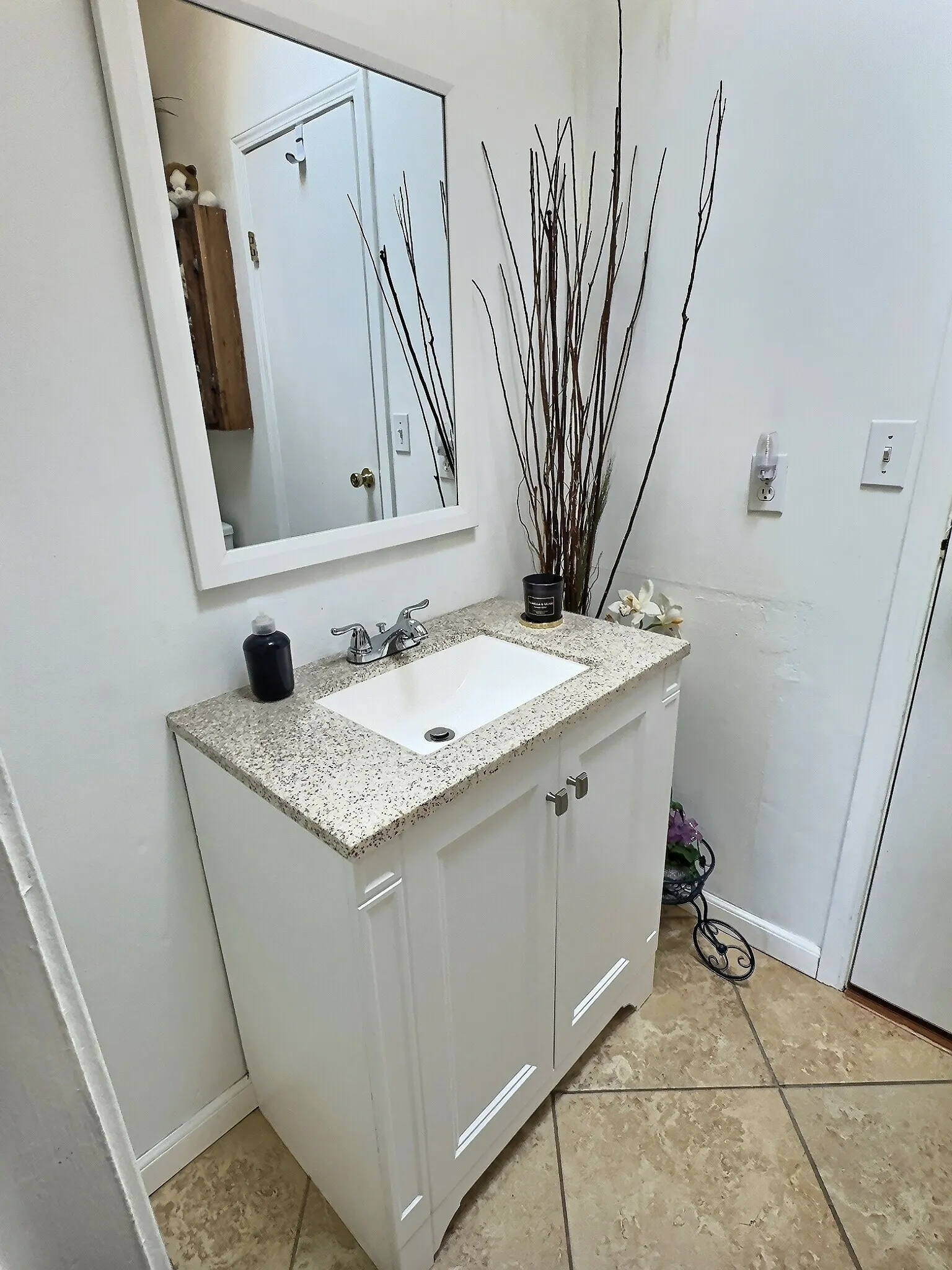 White vanity with a speckled countertop and integrated sink