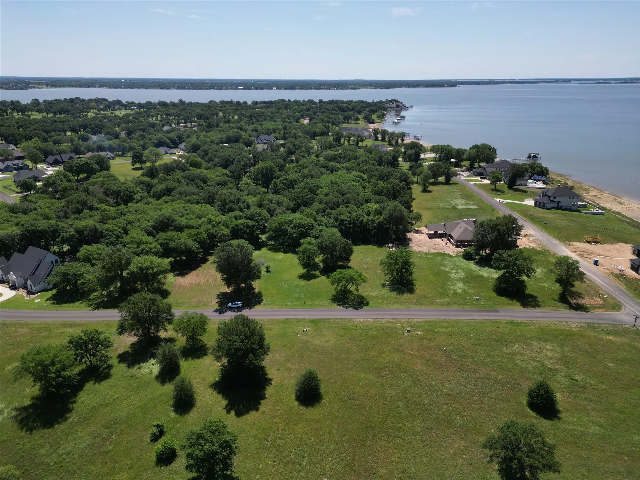 Expansive waterfront property featuring a substantial body of water, mature trees, and a clear blue sky