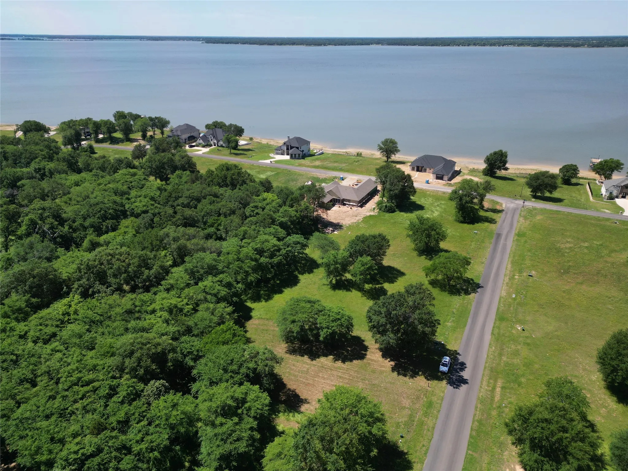 Expansive land parcel featuring dense treelines, open grassy areas, and a paved road
