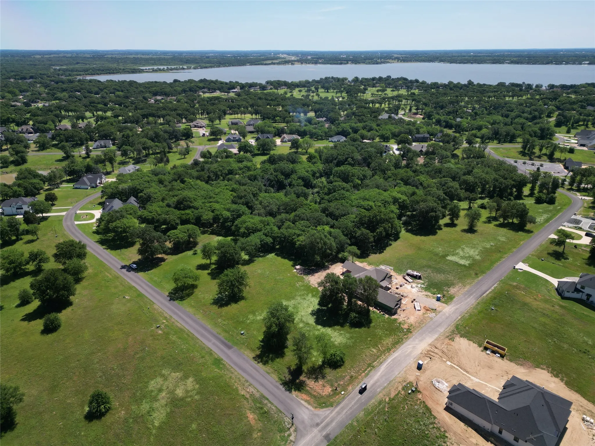 Aerial perspective showcasing expansive green spaces, mature trees, and a distant body of water