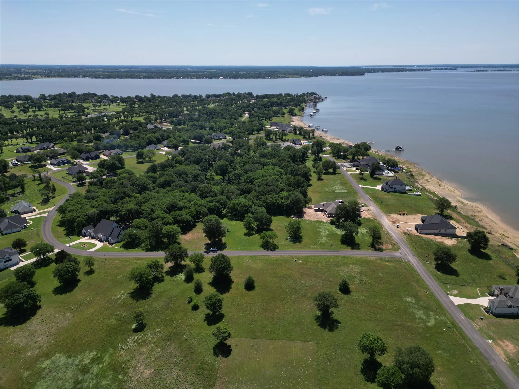 Expansive land parcels featuring mature trees and paved roads, bordering a large body of water