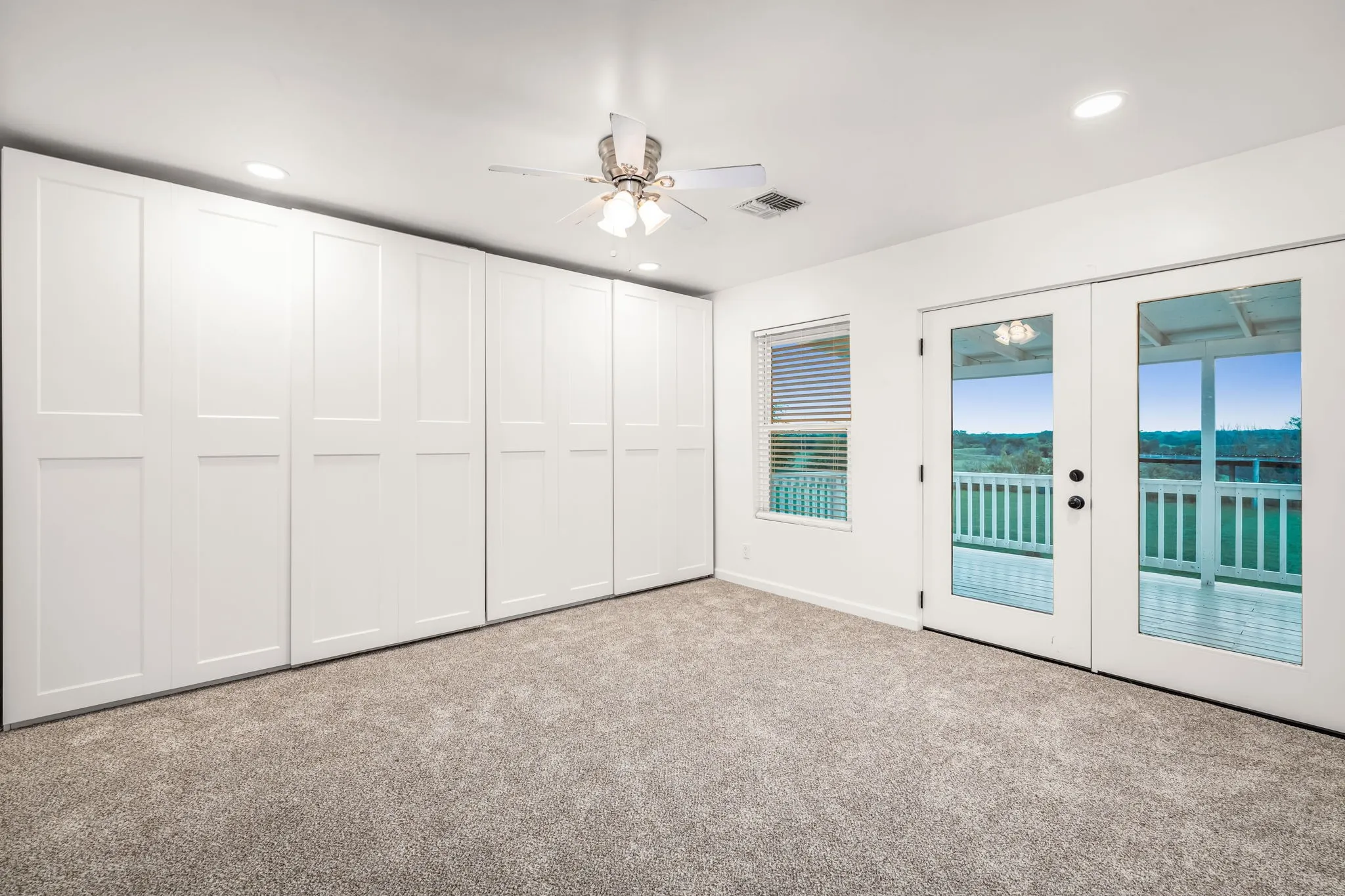 Recessed lighting illuminates this room, featuring a full wall of built-in paneled cabinetry and neutral​​‌​​​​‌​​‌‌​‌‌​​​‌‌​‌​‌​‌​​​‌​​ carpeting
