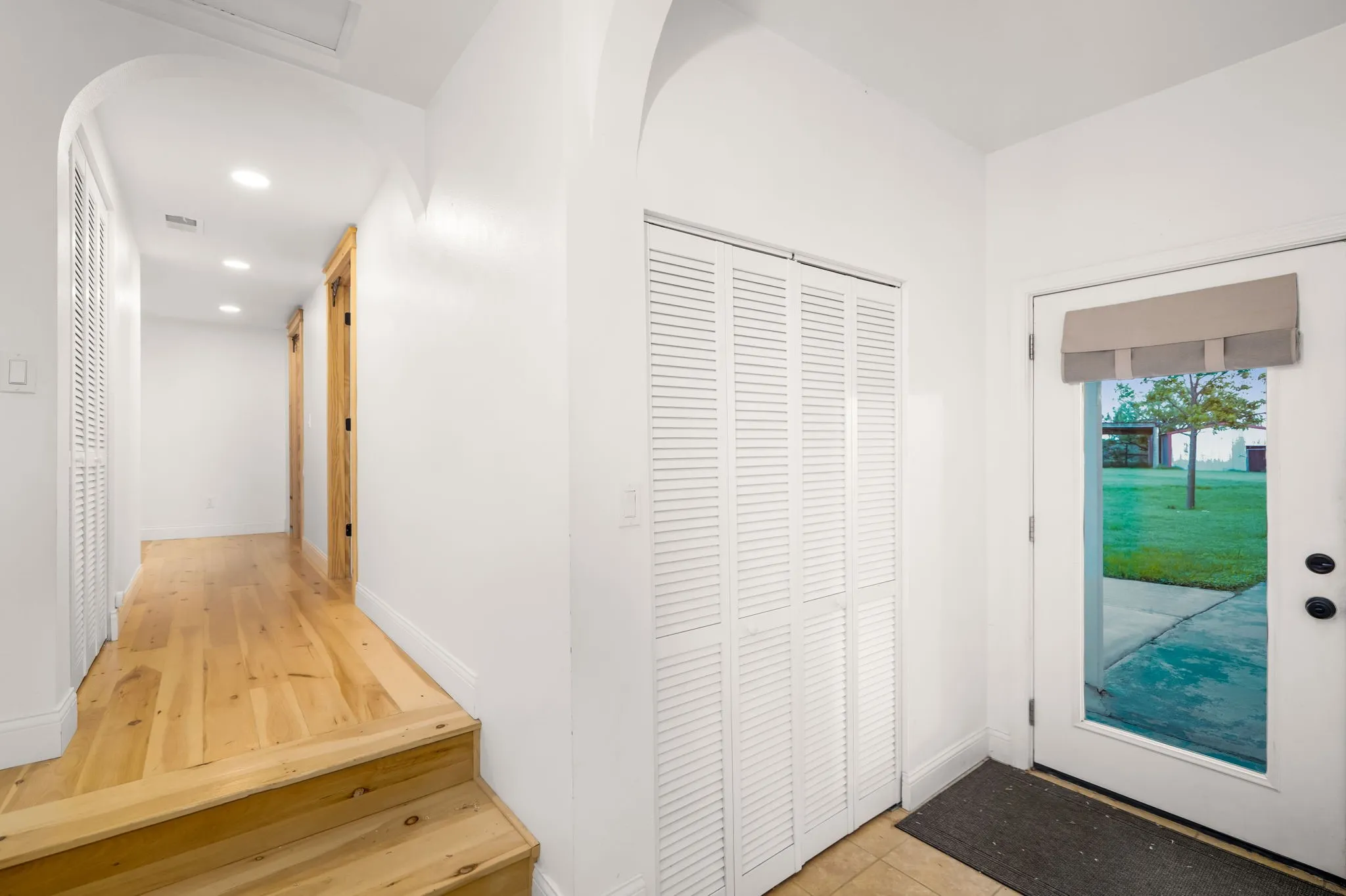 Entryway featuring a glass-paned door, louvered bi-fold closet doors, recessed lighting, and wood-finish flooring